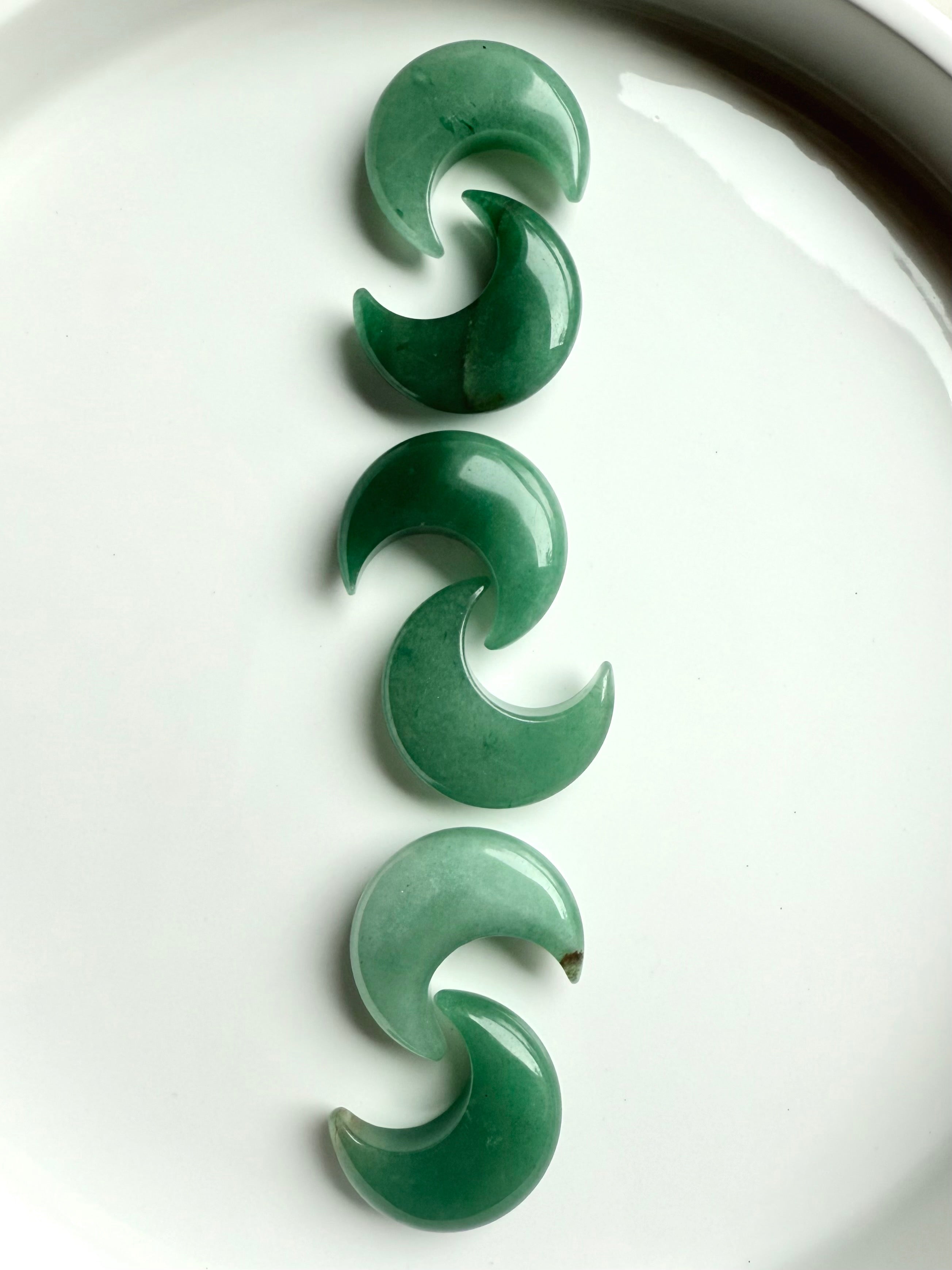 Vertical row of Green Aventurine crescent moons on white background, Heart Chakra crystals for love, luck, and emotional balance