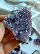Purple amethyst geode cluster held in hand for size reference