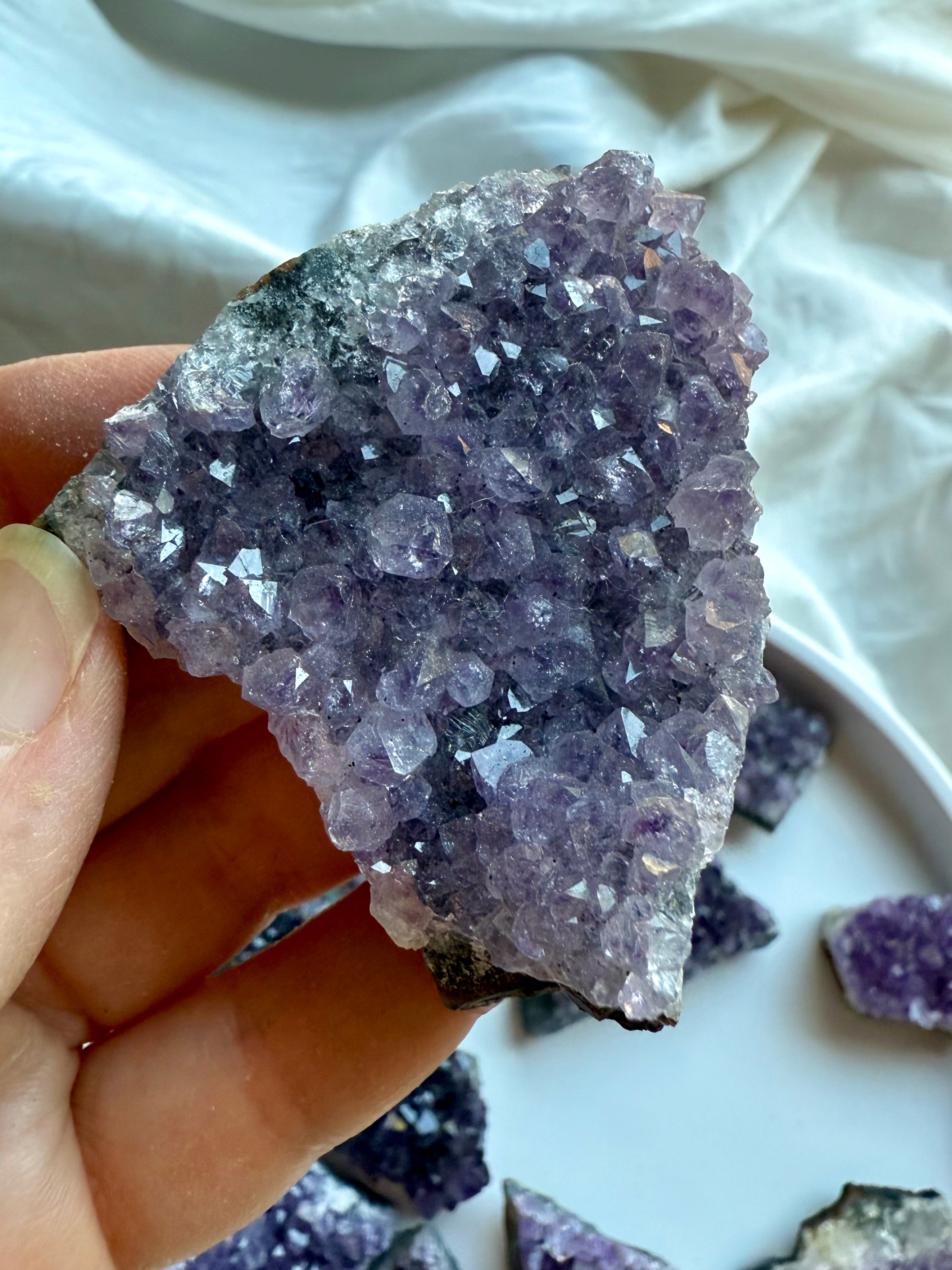 Purple amethyst geode cluster held in hand for size reference