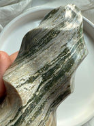 Close-up of Green Ocean Jasper’s intricate mossy striations and glossy carved surfaces in a freeform flame shape.