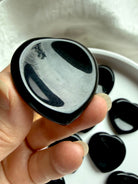 Black obsidian heart worry stone crystal held in hand