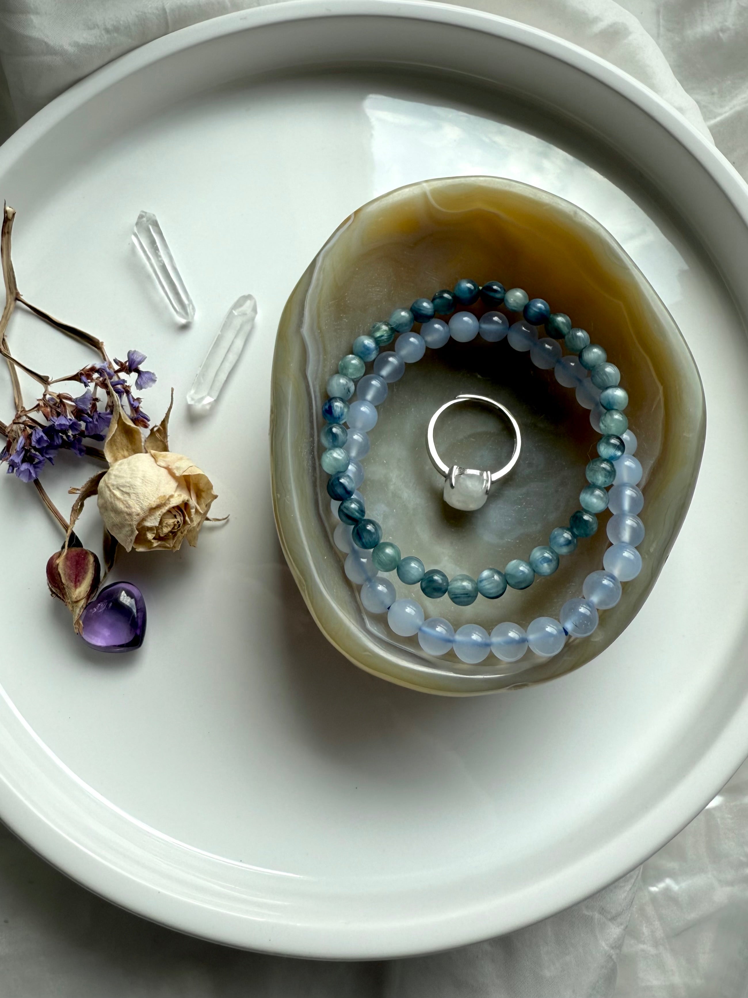 Beige agate crystal bowl filled with gemstone bracelets and ring – hand-carved gemstone dish for grounding and balance