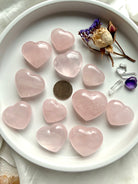 Rose quartz heart carvings shown with a US quarter for scale in soft blush pink crystals