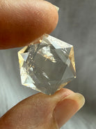 Clear faceted Citrine hexagon held to the light showing reflective facets and natural internal crystal patterns