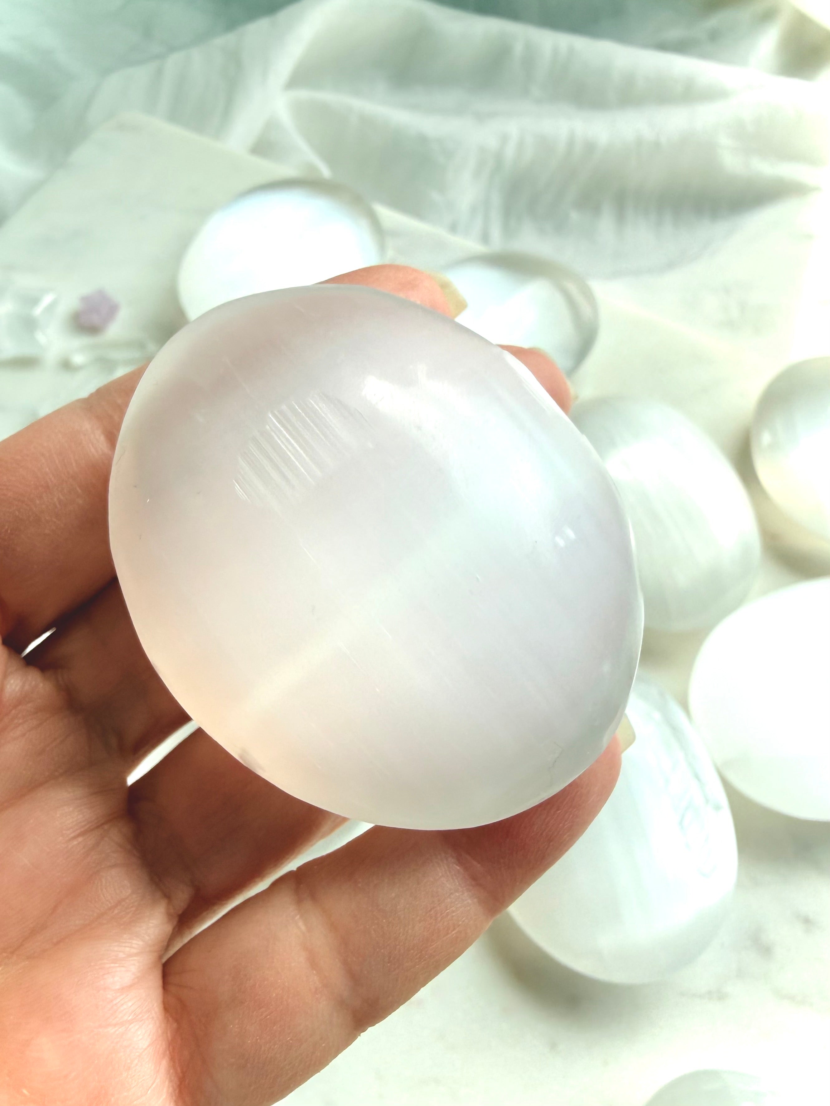 Large polished Selenite palm stone with soft translucency and luminous white satin spar crystal in natural light