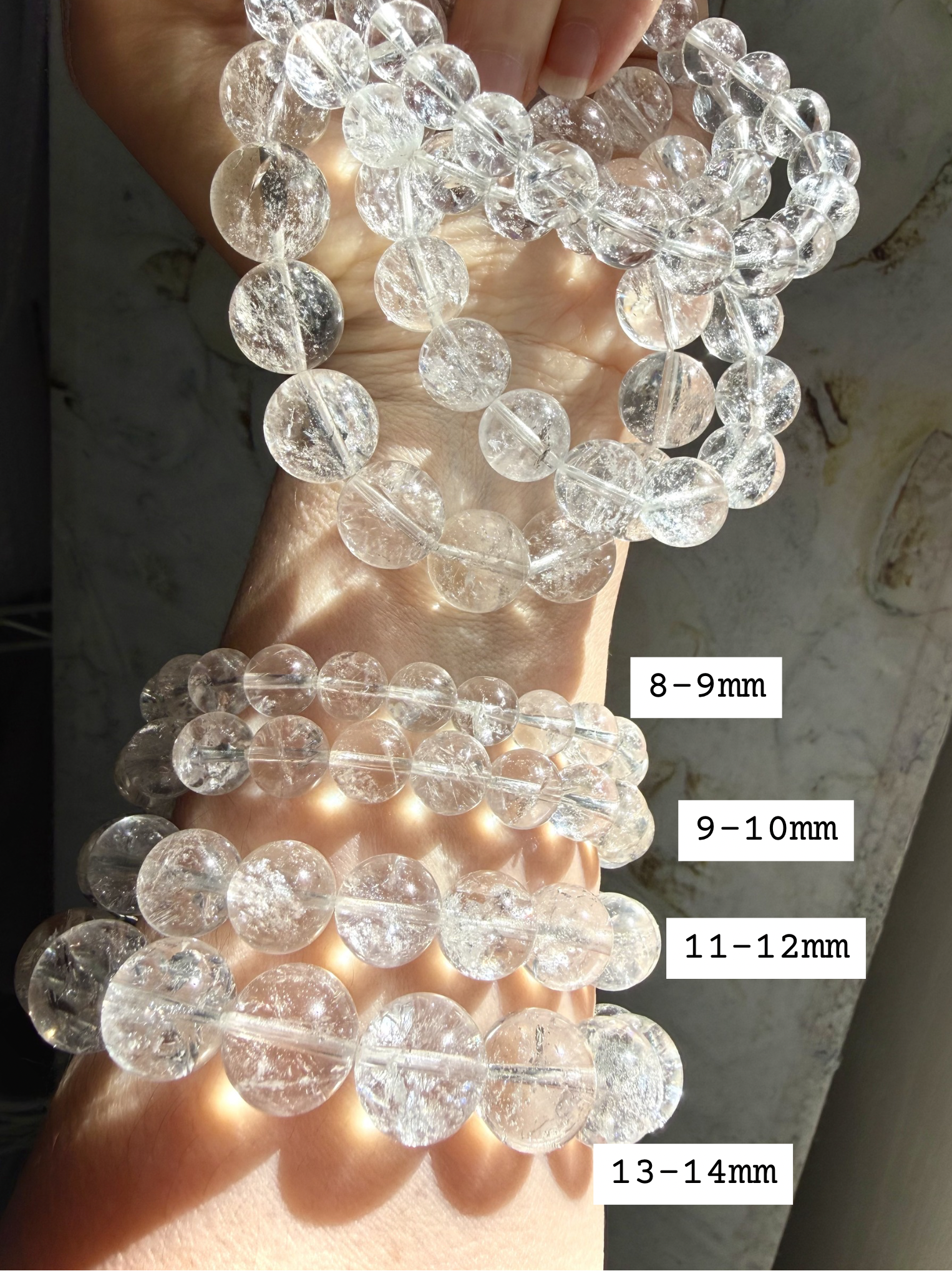 High clarity Clear Quartz bracelet stack shown bead sizes marked 8-14mm for comparison, and iridescent rainbow reflections