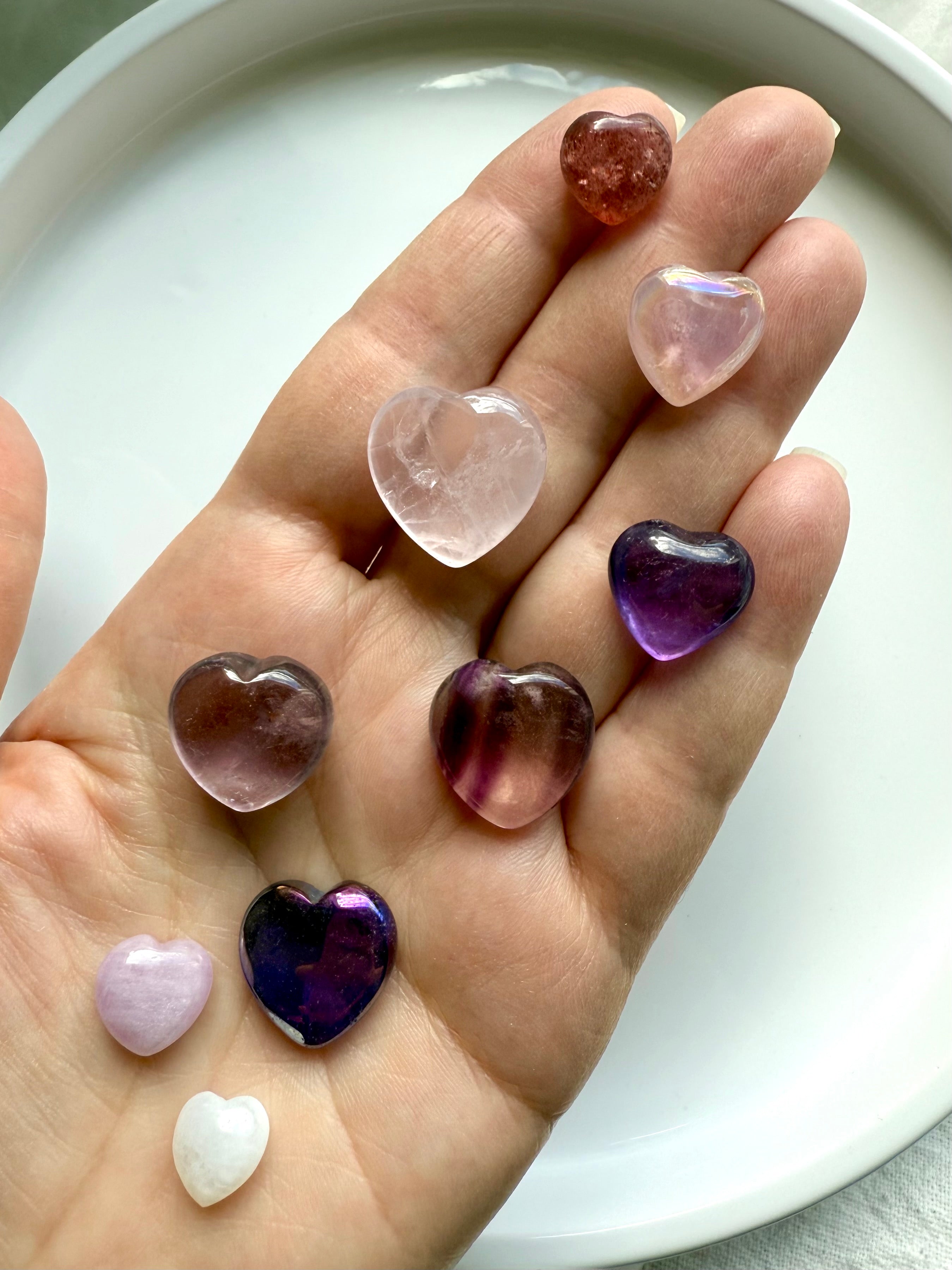 Pink and purple mini crystal hearts displayed in hand, premium gemstone carvings for love and healing.