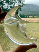 Clear Quartz Moon Face carving glowing in natural light with exceptional clarity and detailed celestial crystal craftsmanship