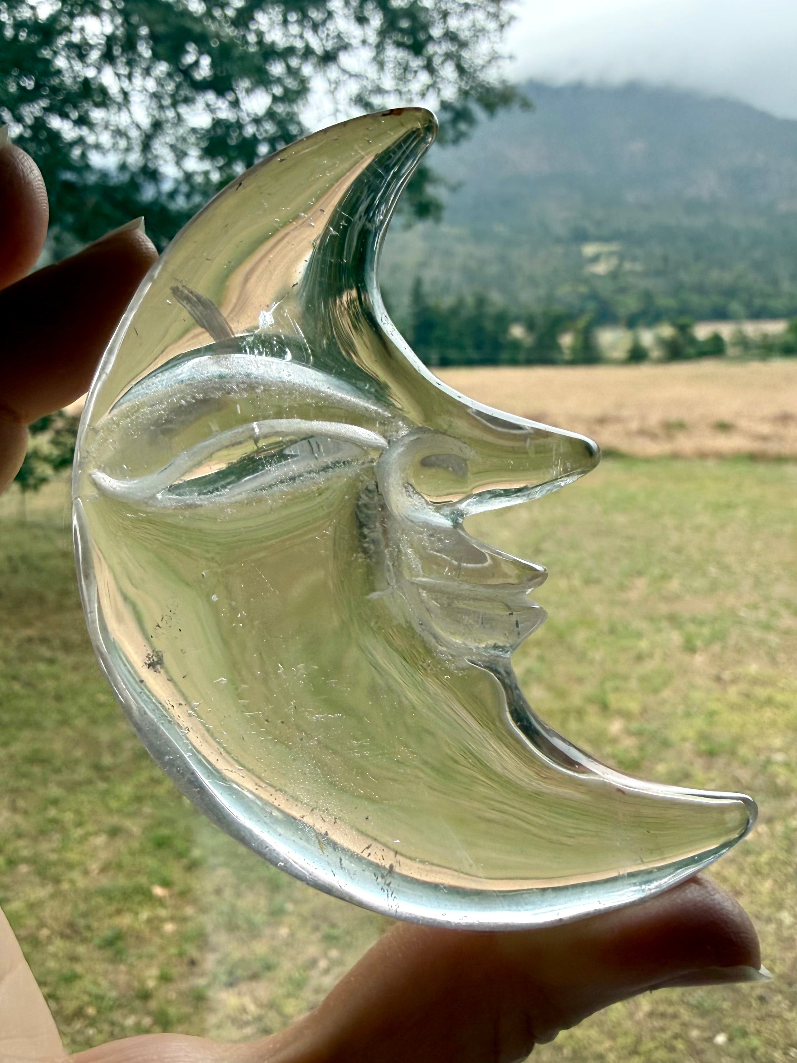 Clear Quartz Moon Face carving glowing in natural light with exceptional clarity and detailed celestial crystal craftsmanship