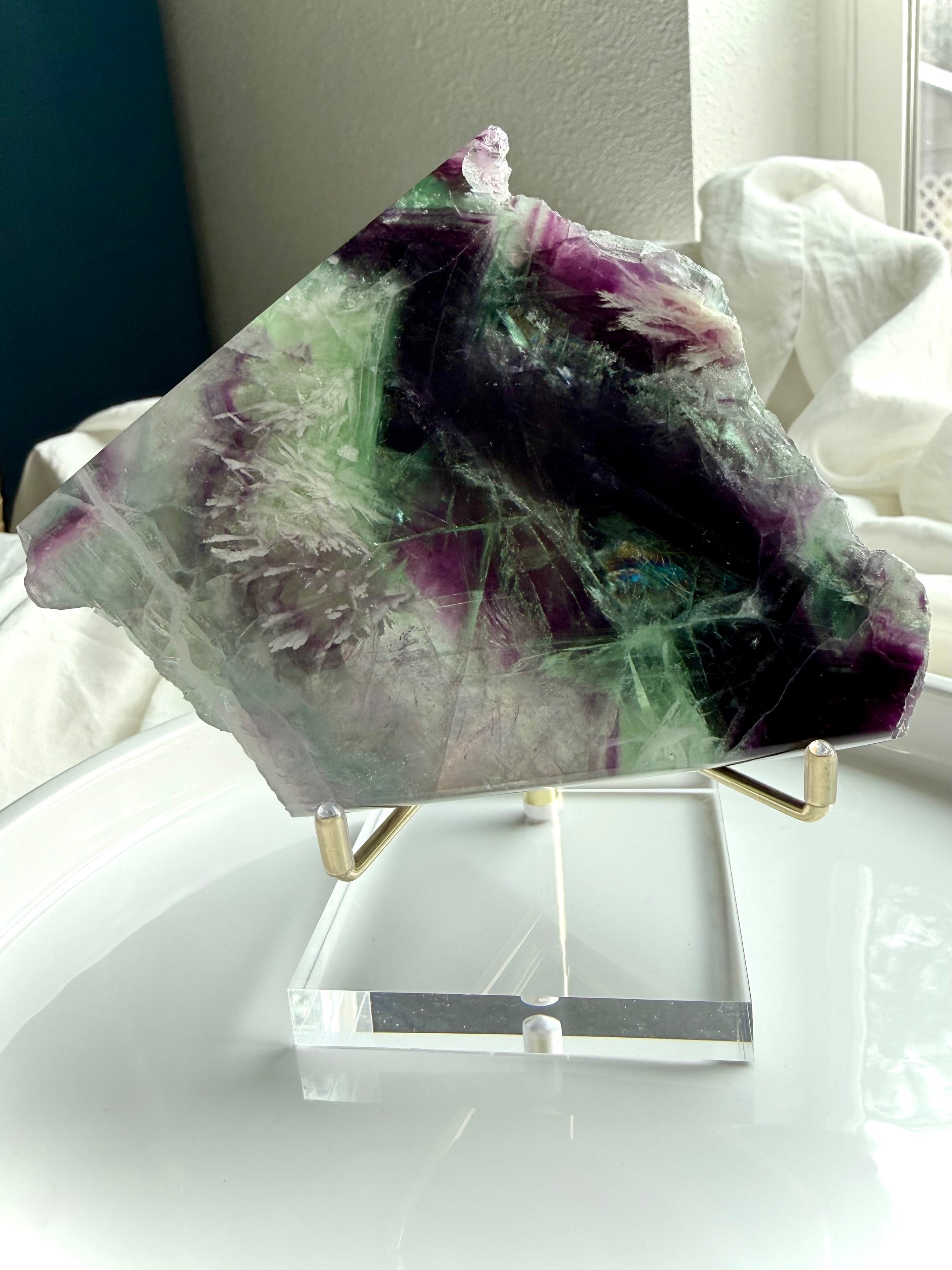 One of a kind green and purple fluorite slab shown on an elegant display stand