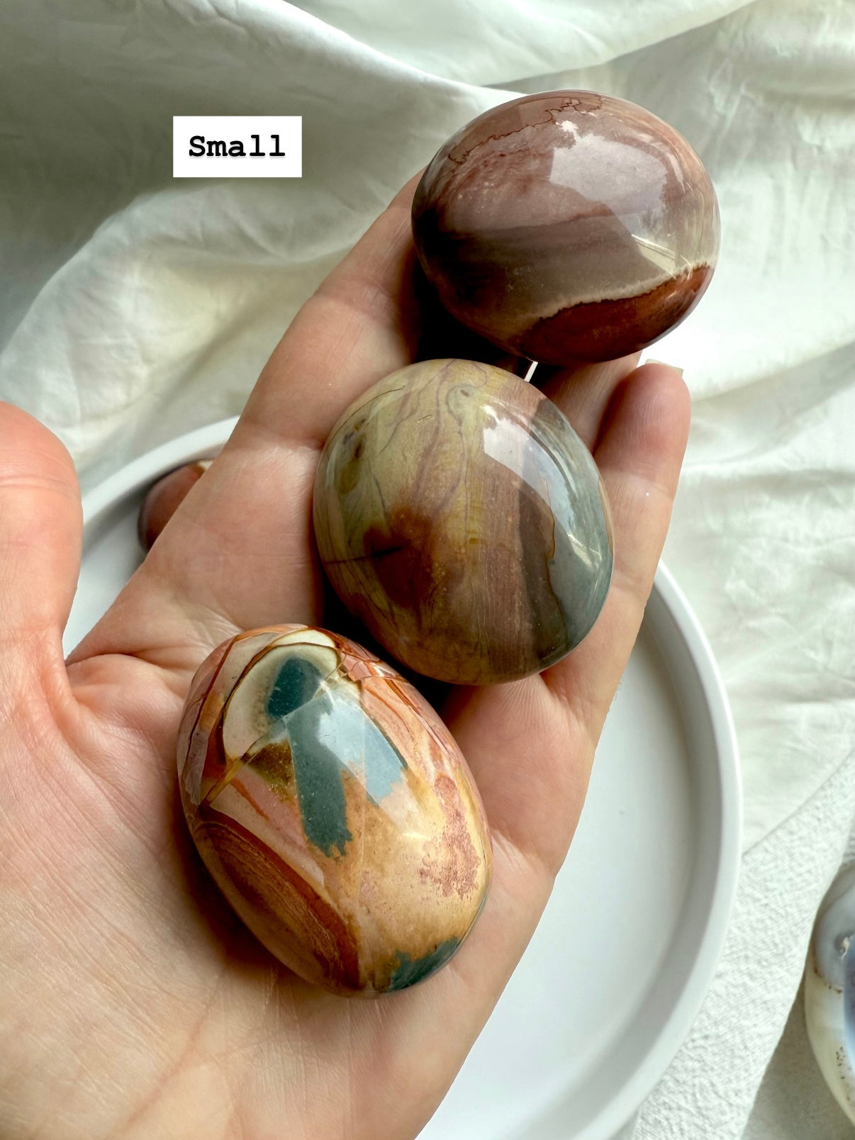 Small Polychrome Jasper palm stone in hand with soft, earthy colors and grounding crystal energy.