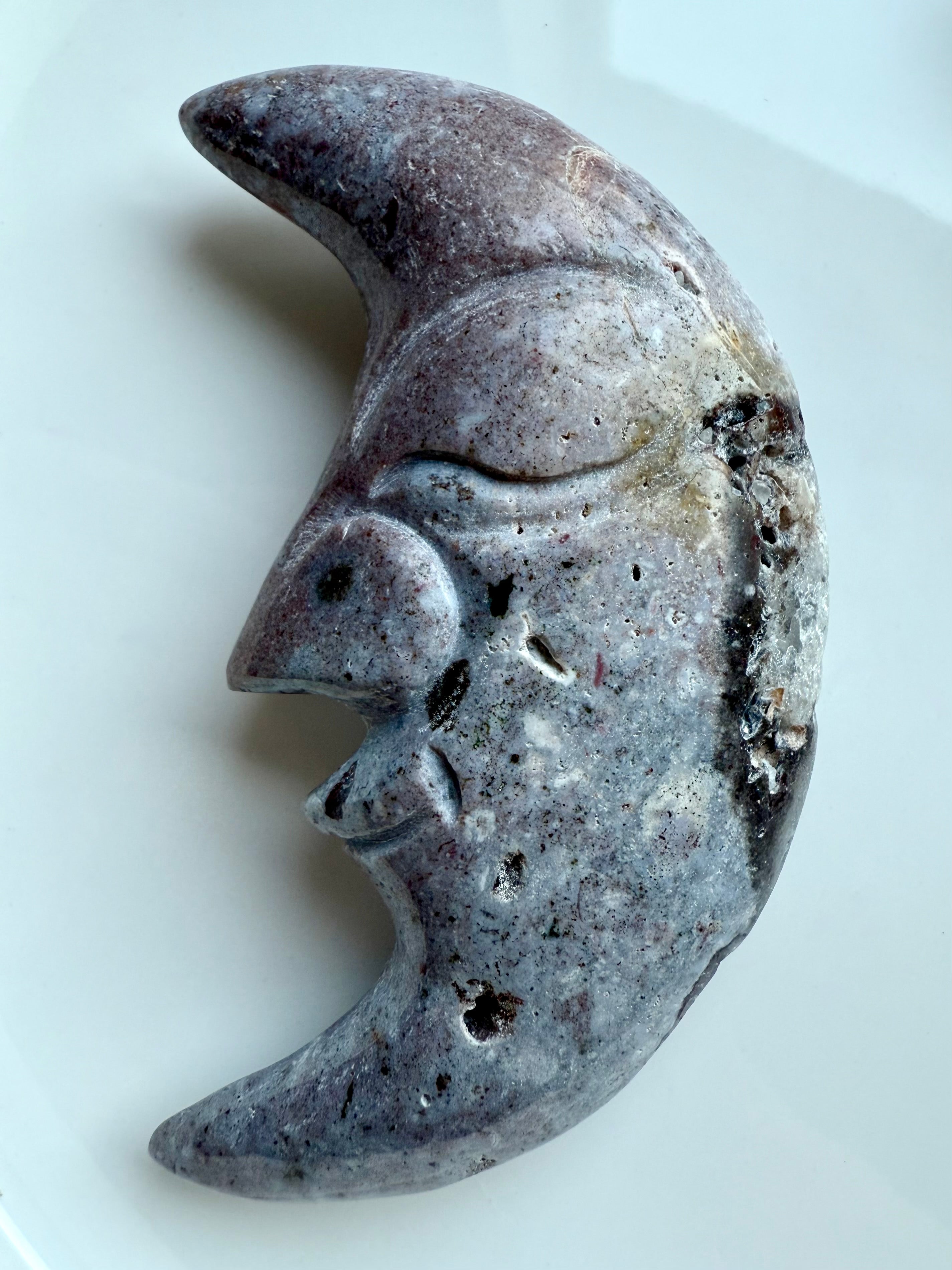 Polished Ocean Jasper crescent moon crystal carving in purple hues shown on white.