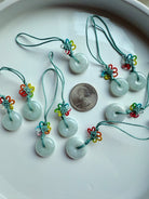 Jade donut charms with colorful knots arranged in a group beside a US quarter for size reference