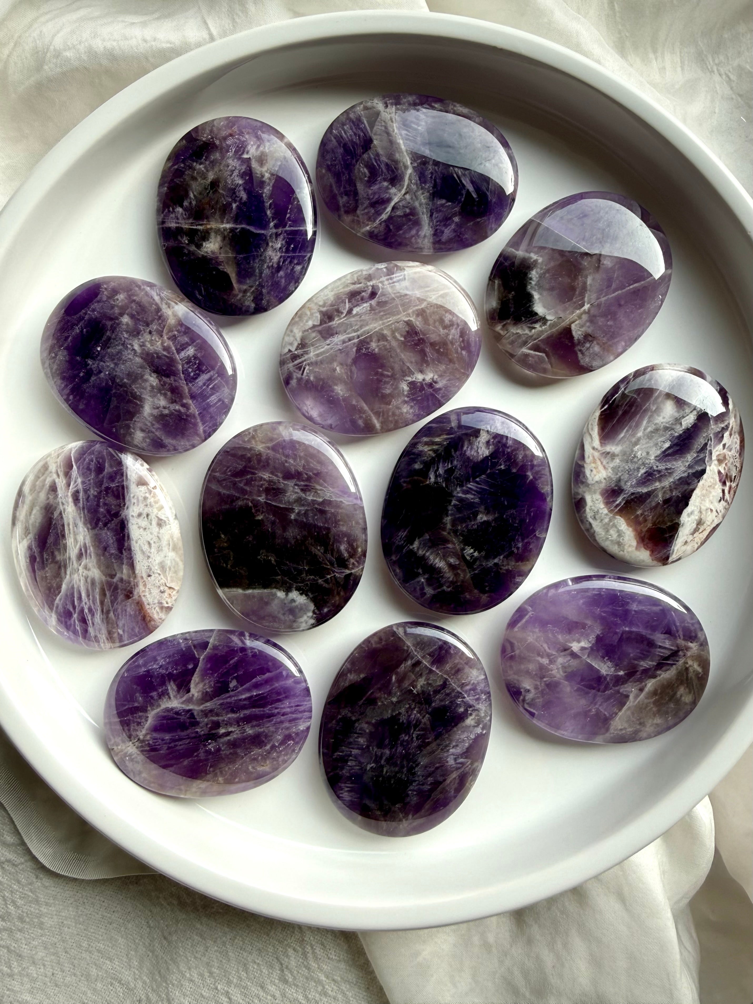 Dream amethyst flat palm stones showing natural variation in purple, lavender, white, and smoky banding, polished pocket crystals for calm and restful sleep