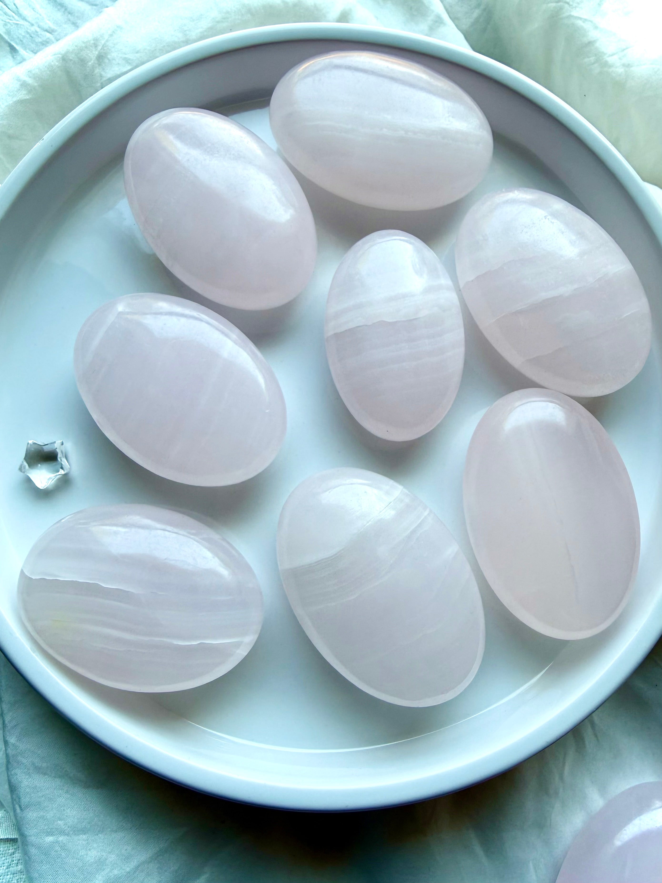 Mangano Calcite palm stones with soft blush pink banding for emotional healing, self-love and Heart Chakra