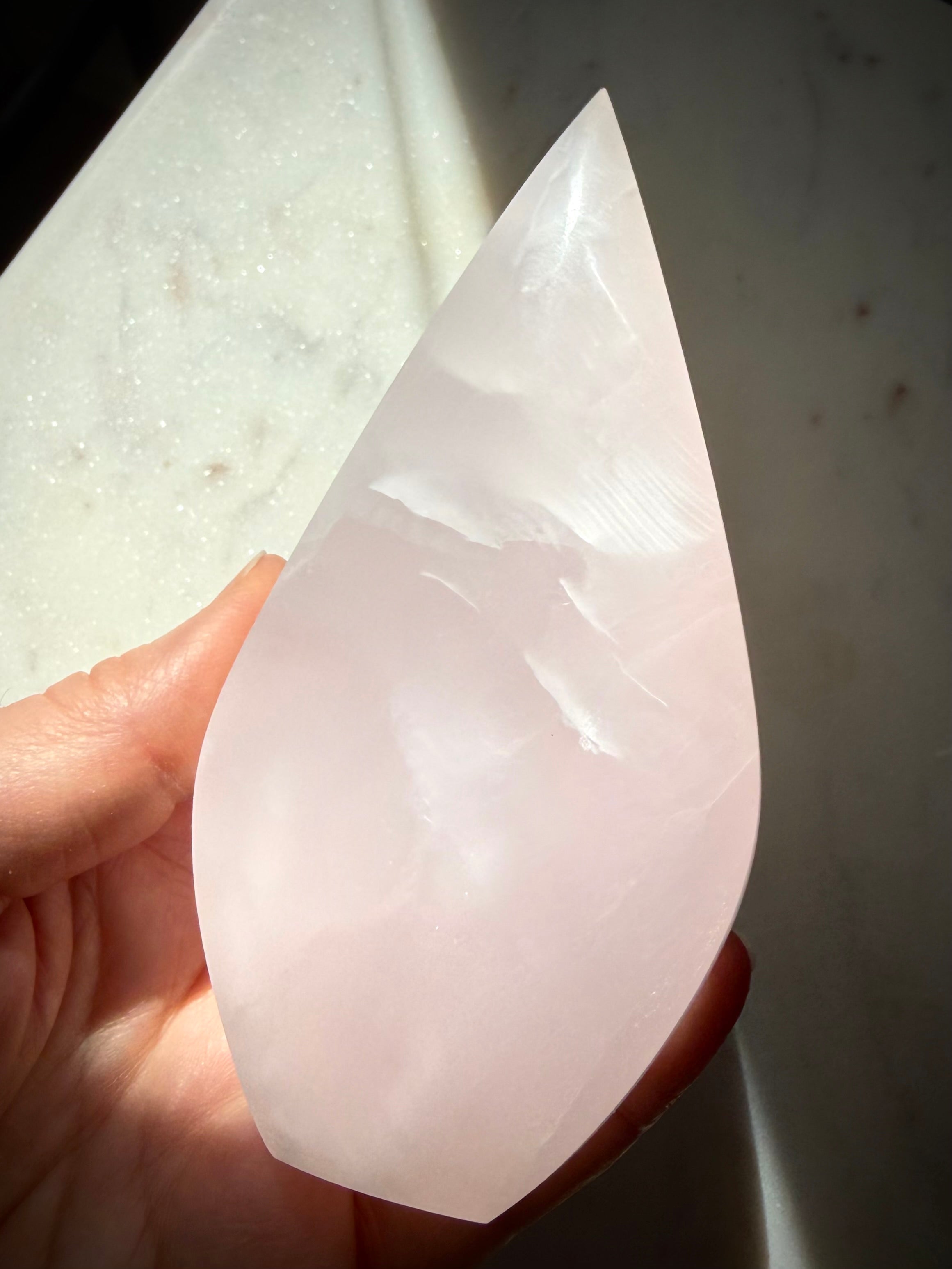 Polished Mangano Calcite flame held in hand showing graceful shape, natural beauty and emotional healing energy