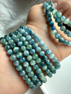 crystal bracelets stacked on arm in natural lighting showcasing the soothing aqua, seafoam, and indigo striations of kyanite beads