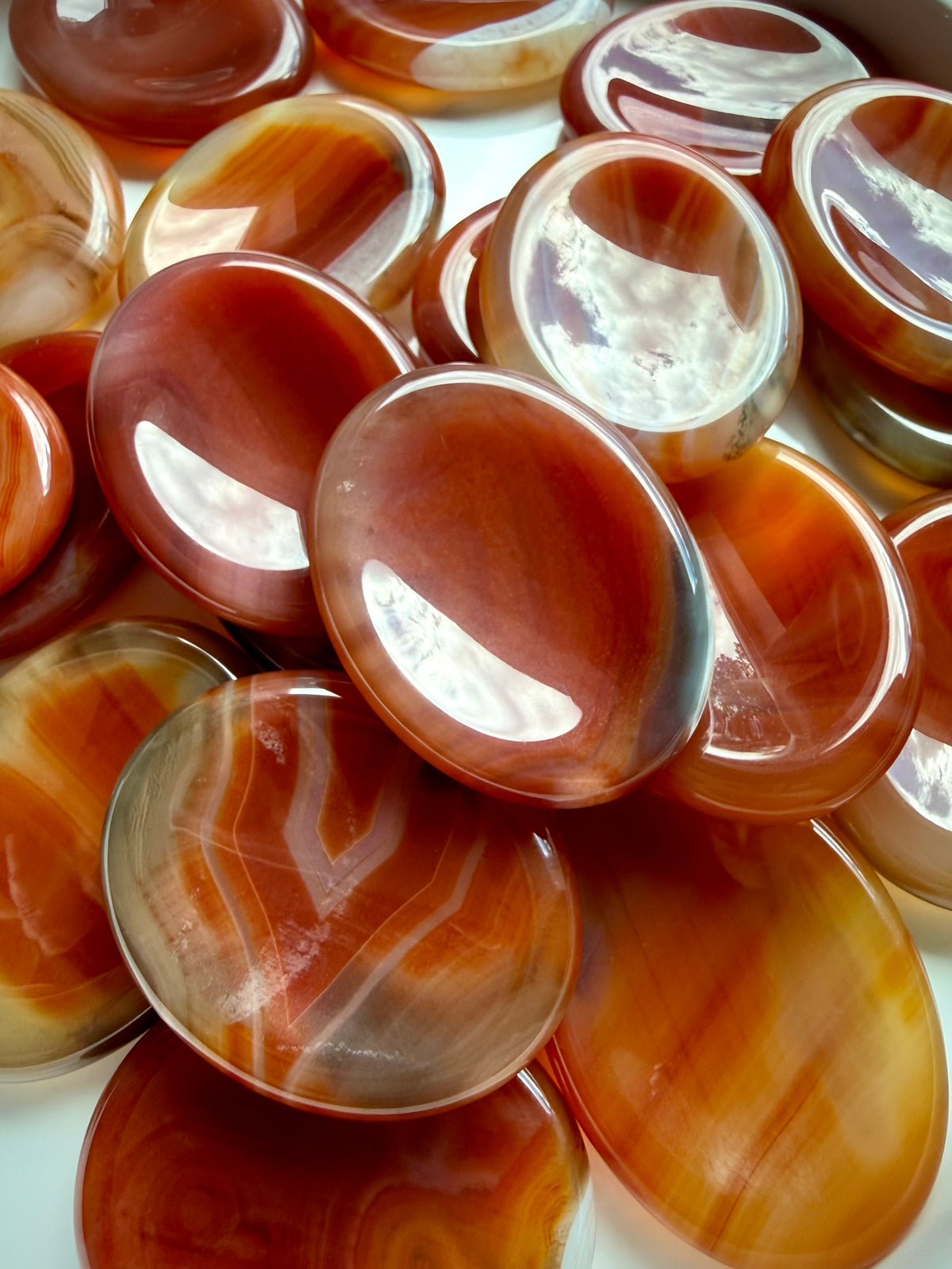Carnelian Agate worry stones with smooth oval shapes, thumb indentations and varied red-orange banded patterns