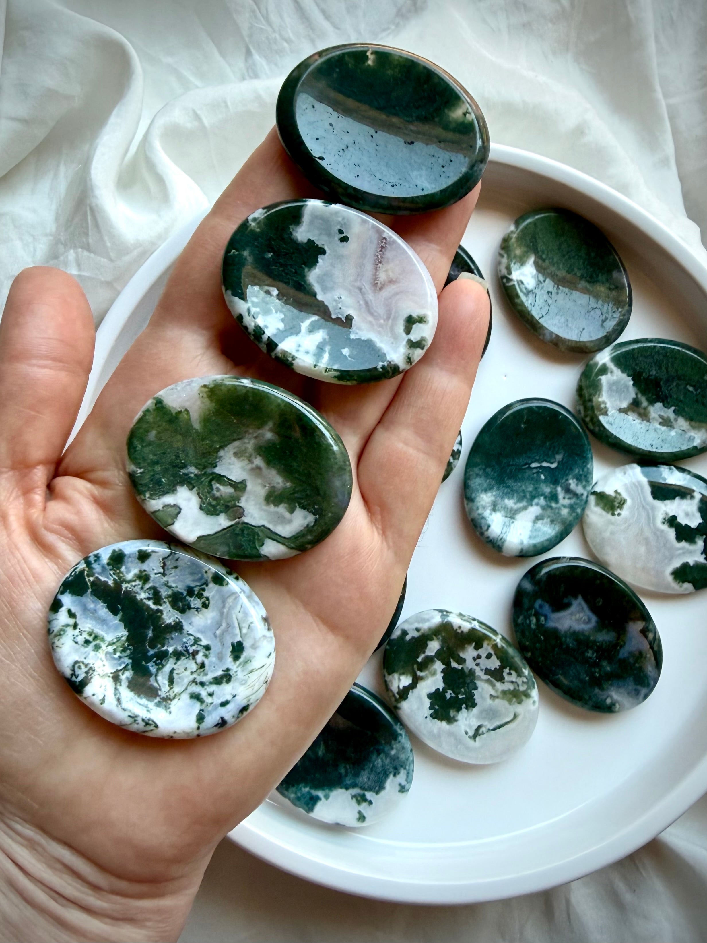 Moss Agate oval worry stone shown on hand with translucent quartz and landscape-like moss inclusions