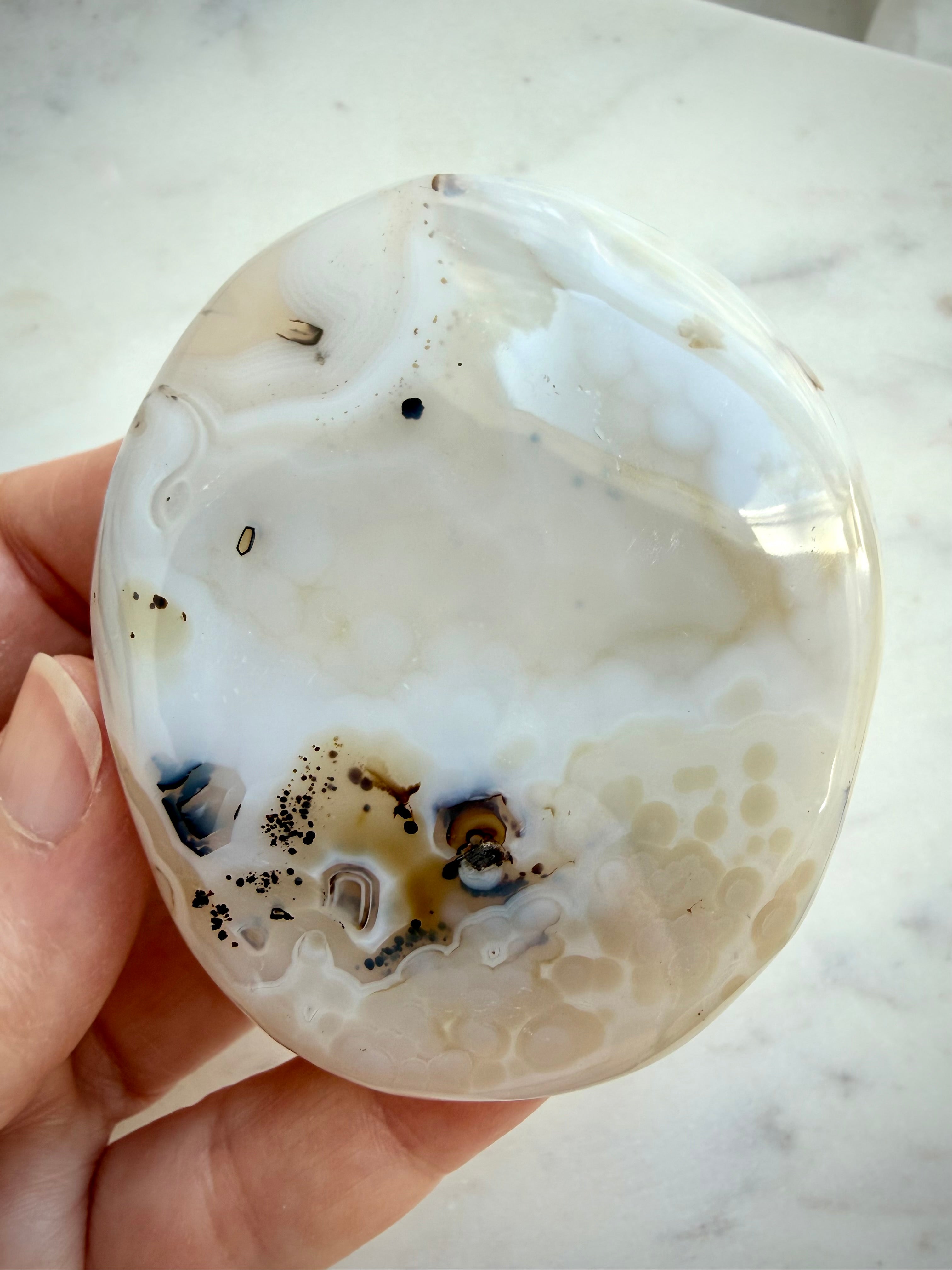 Polished Dendritic Agate crystal with soft cream and gray banding, scattered dark inclusions and organic contours