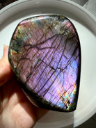 Pastel Labradorite crystal held in hand with soft pink, purple and lavender flash shifting across the polished face