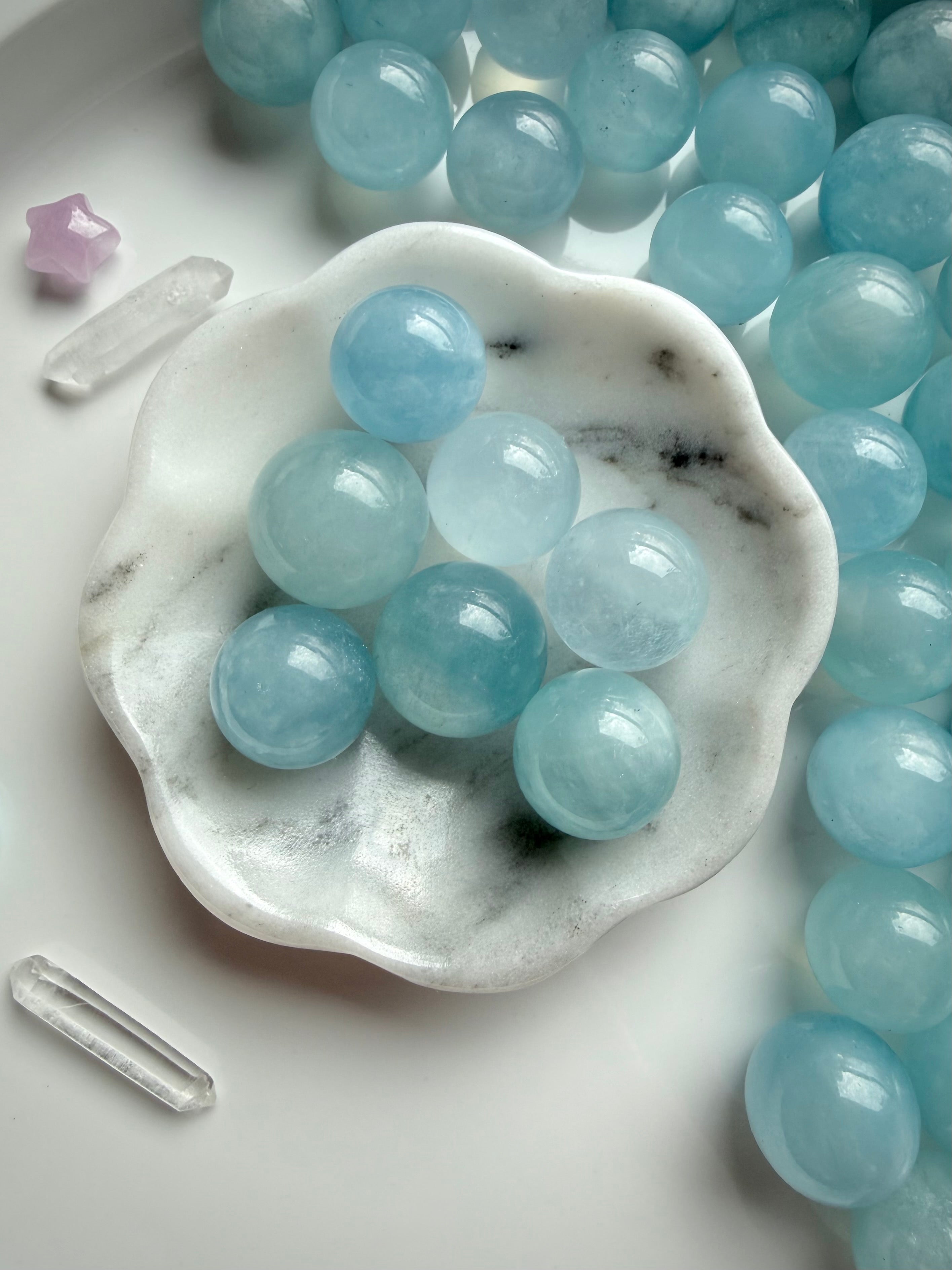 Aquamarine mini crystal spheres in calming ocean blue displayed in marble bowl – March birthstone crystal balls