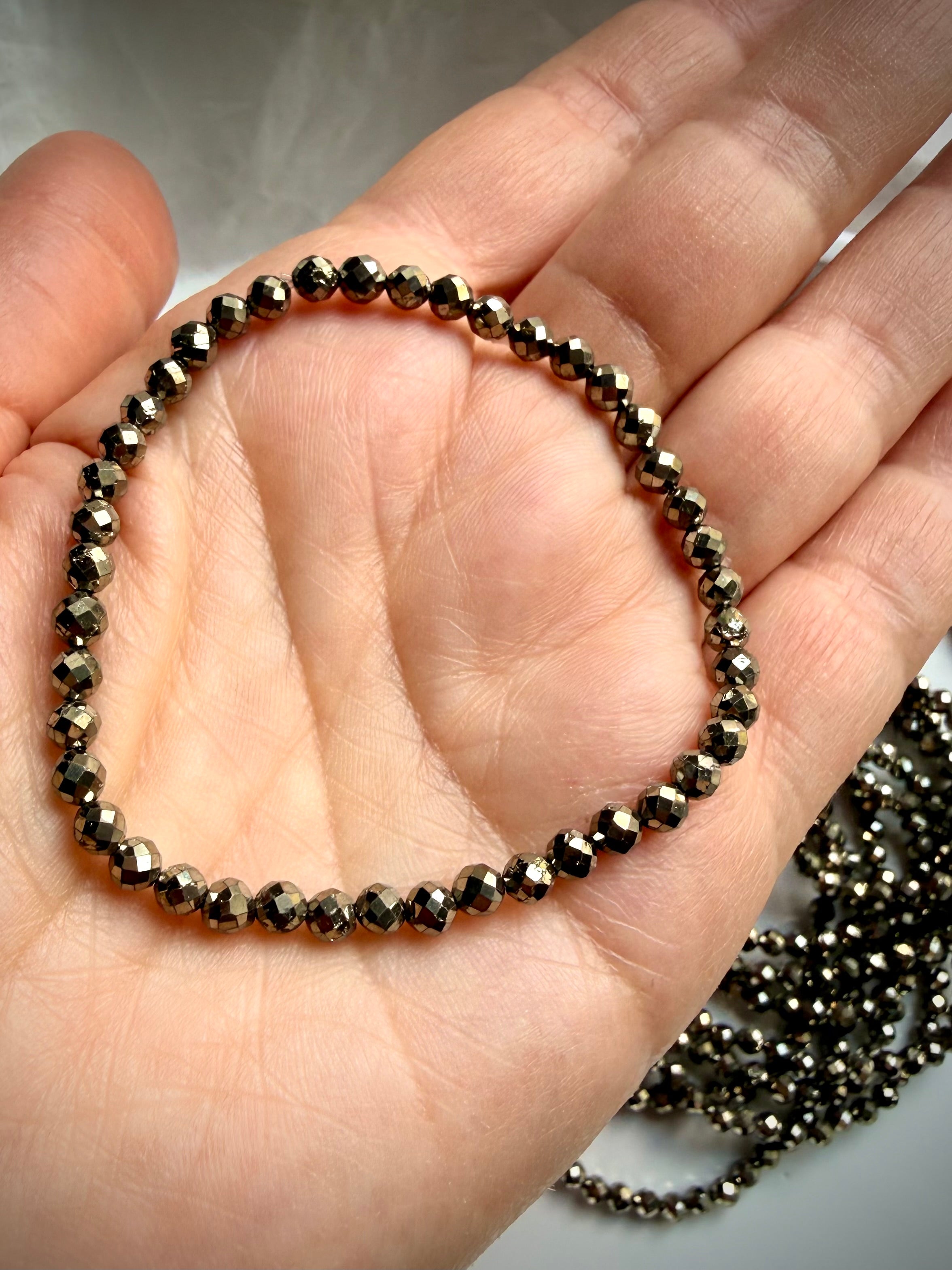 single faceted pyrite bracelet in hand showing small reflective beads and stretch fit crystal jewelry