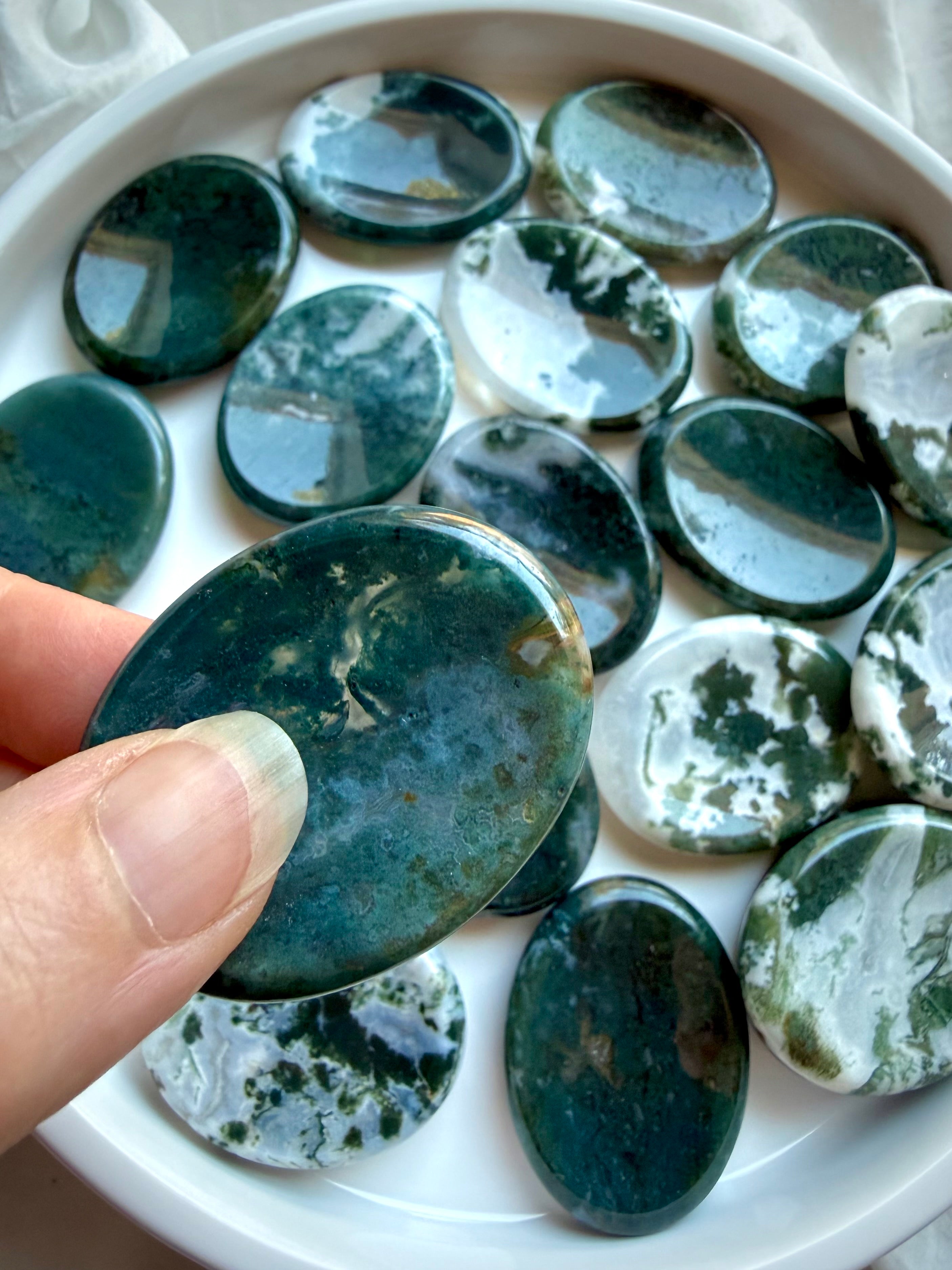 Dark green Moss Agate oval worry stone held in hand with natural moss inclusions and polished finish