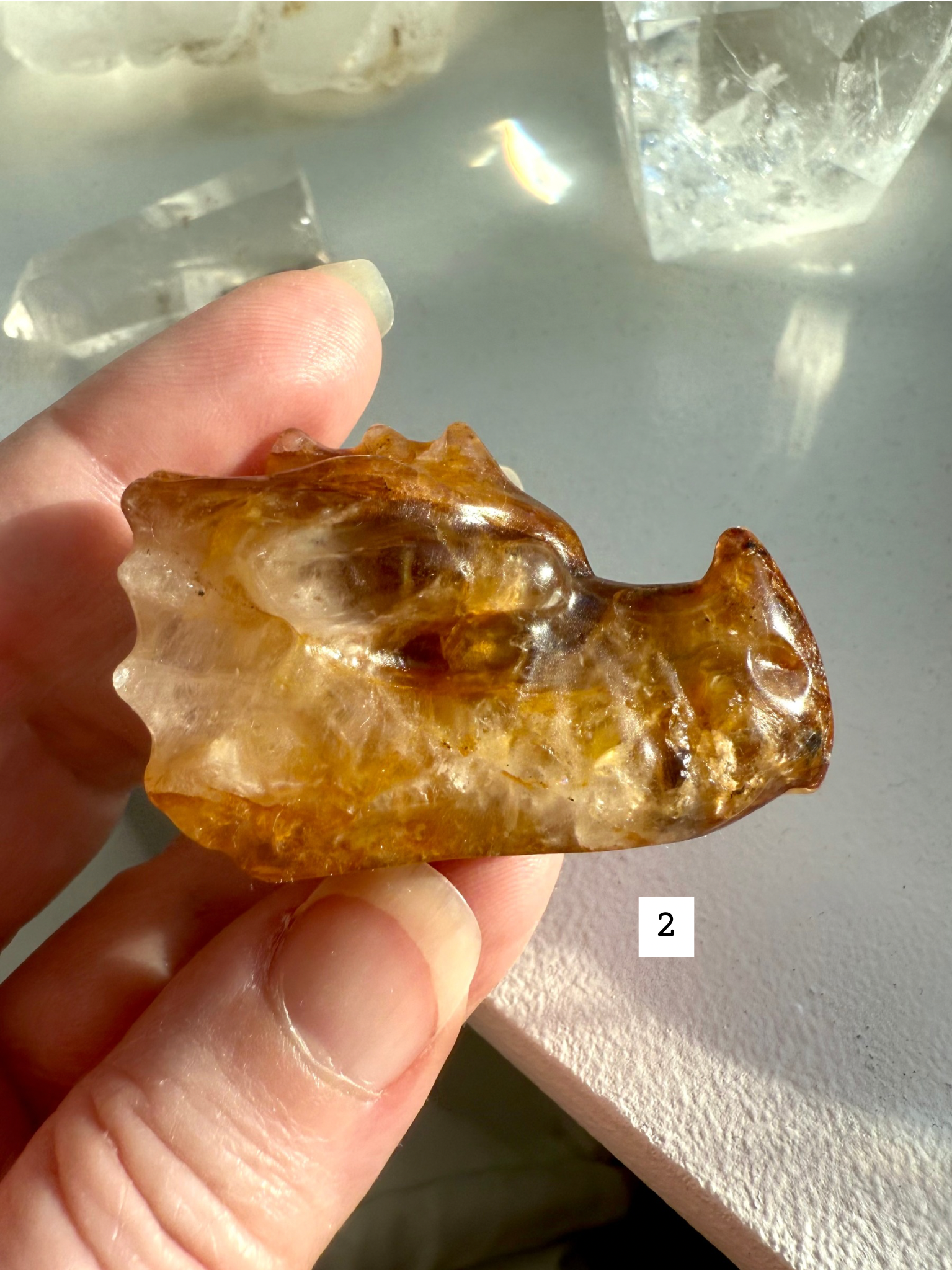 Golden Healer Quartz dragon head carving with dark golden hues, shown in hand — polished crystal dragon figurine for protection and empowerment.