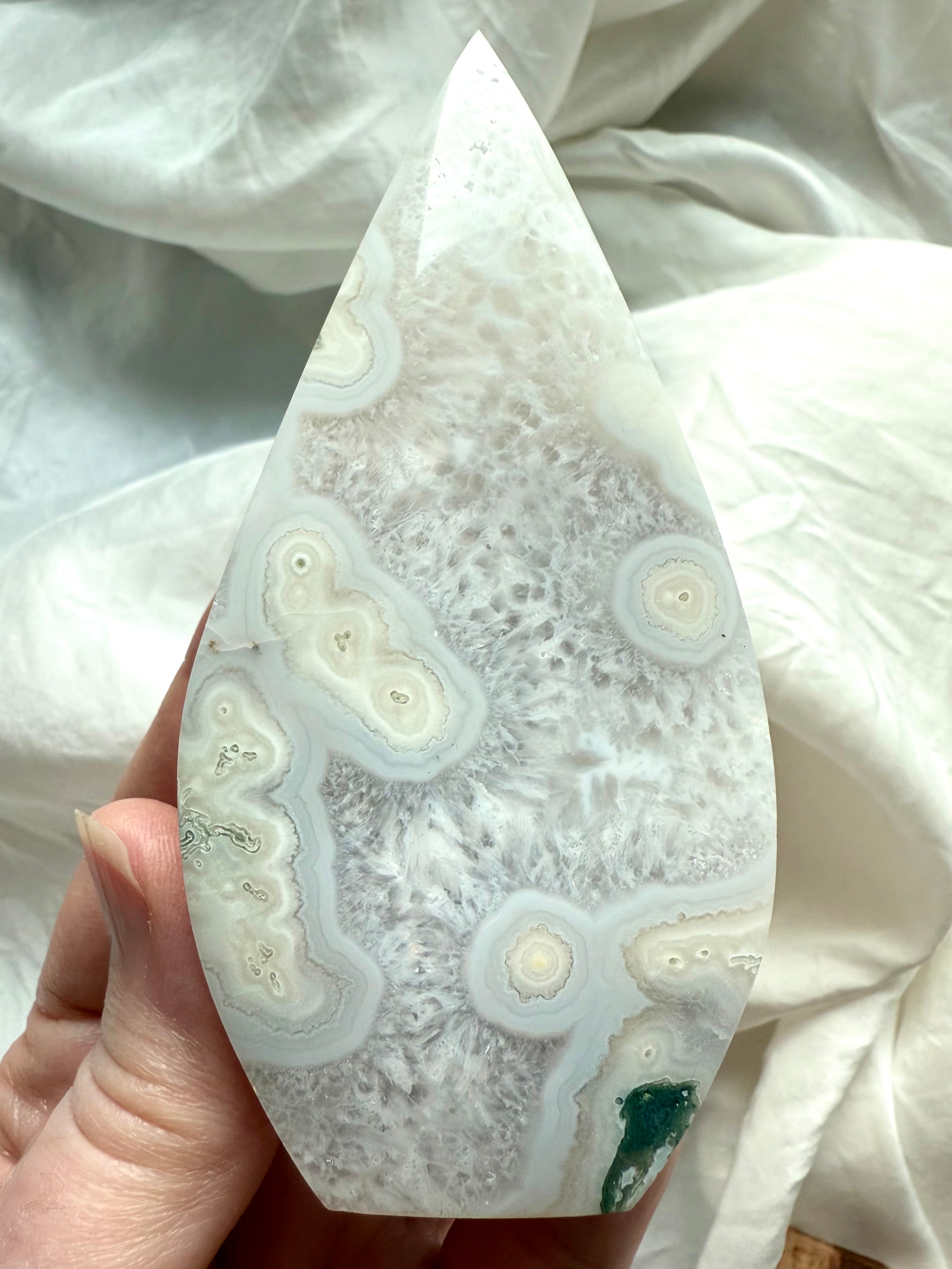 White orbicular Moss Agate flame held in hand for size and detail reference