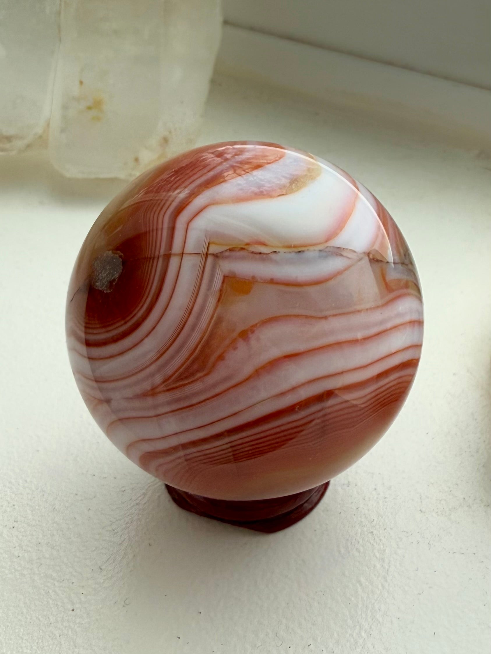 A stunning carnelian sphere with vibrant reddish orange colors + contrasting white banding