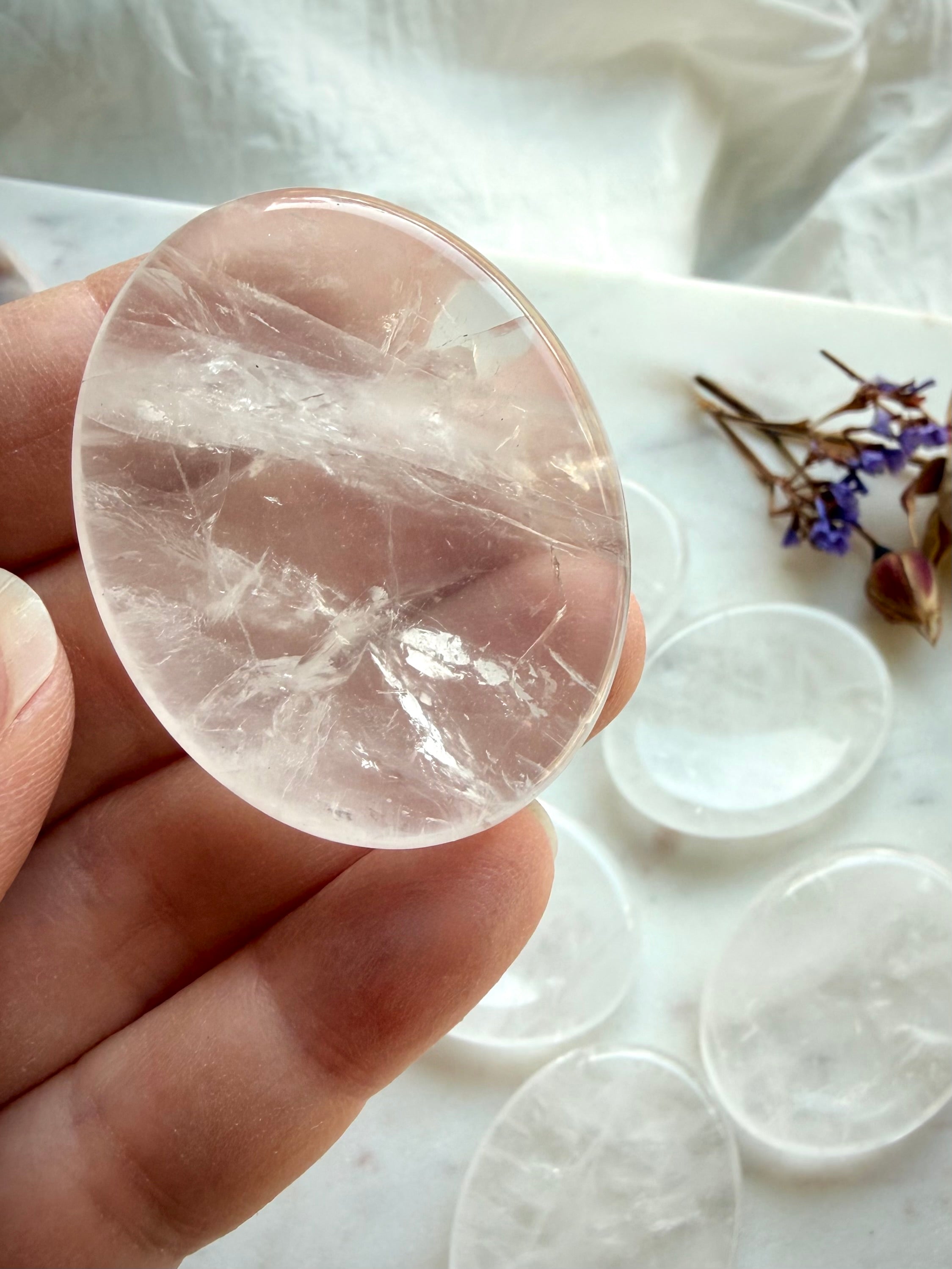 closeup of a clear quartz worry stone in hand showing oval shape for clarity focus & energy healing