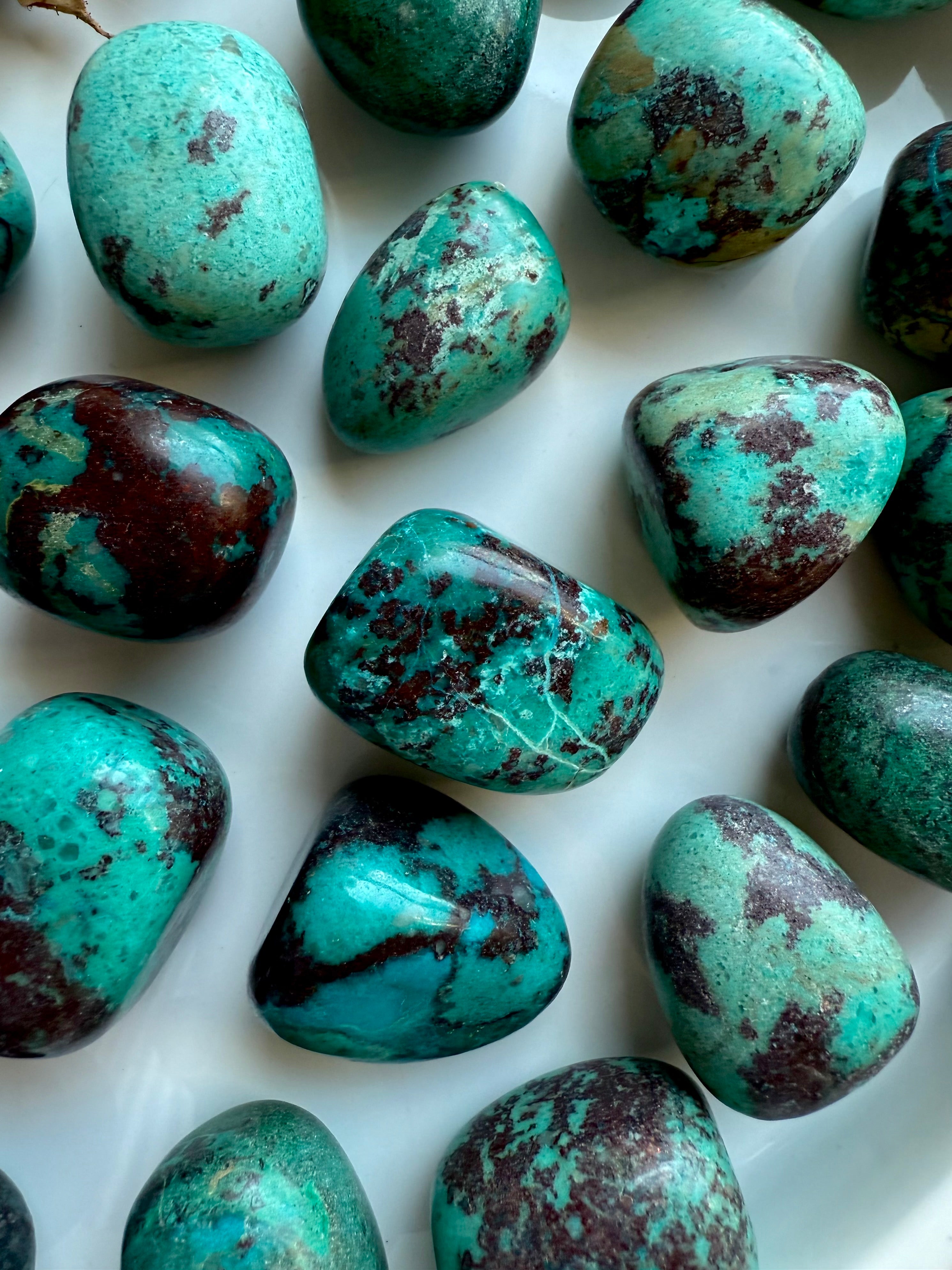 Group of polished Chrysocolla tumbled stones with earthy turquoise and deep red inclusions, hand-selected crystals for healing and grounding.