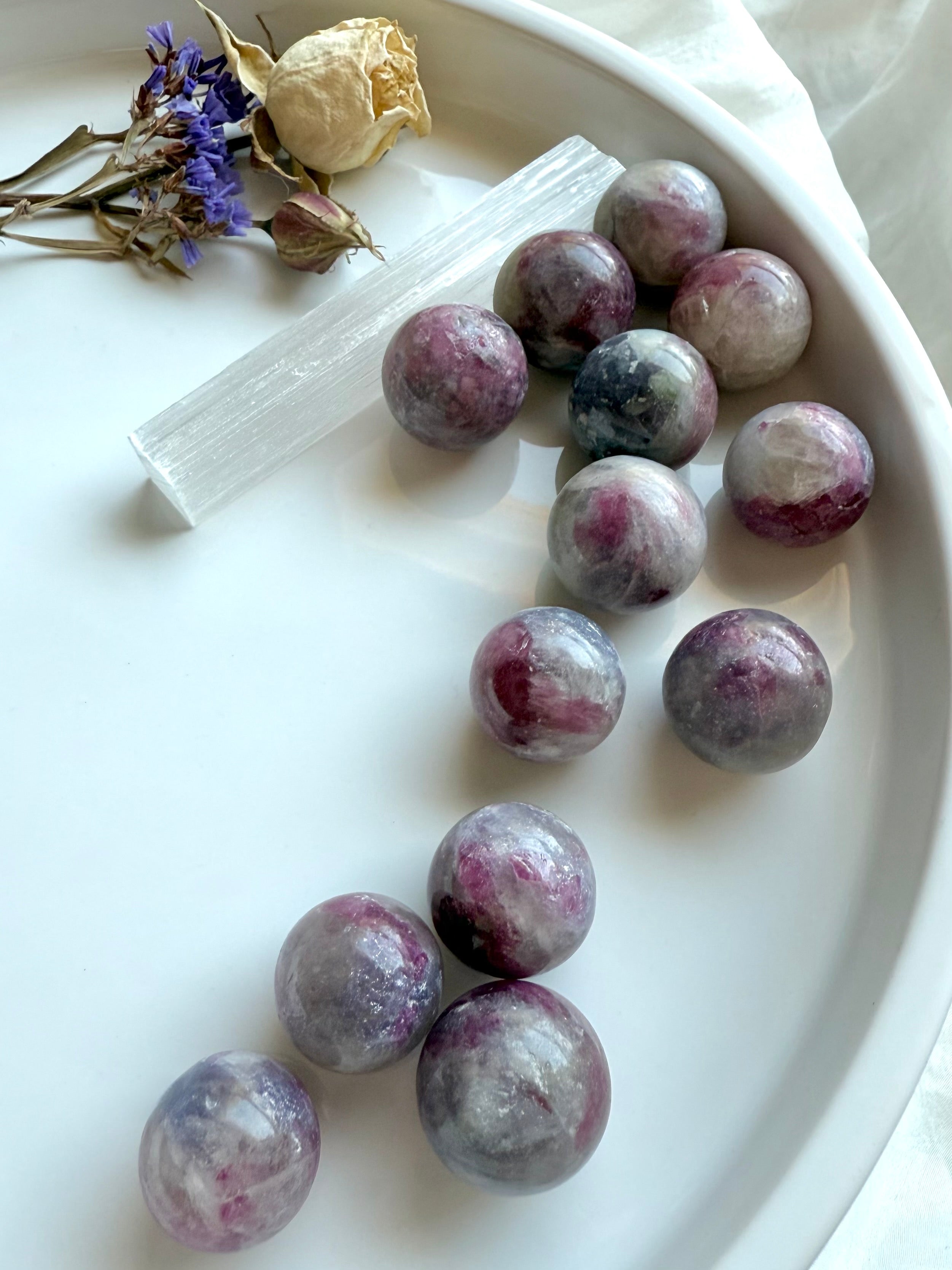 Mini Unicorn Stone spheres styled in a white tray with selenite wand, dried rose, and purple statice flowers