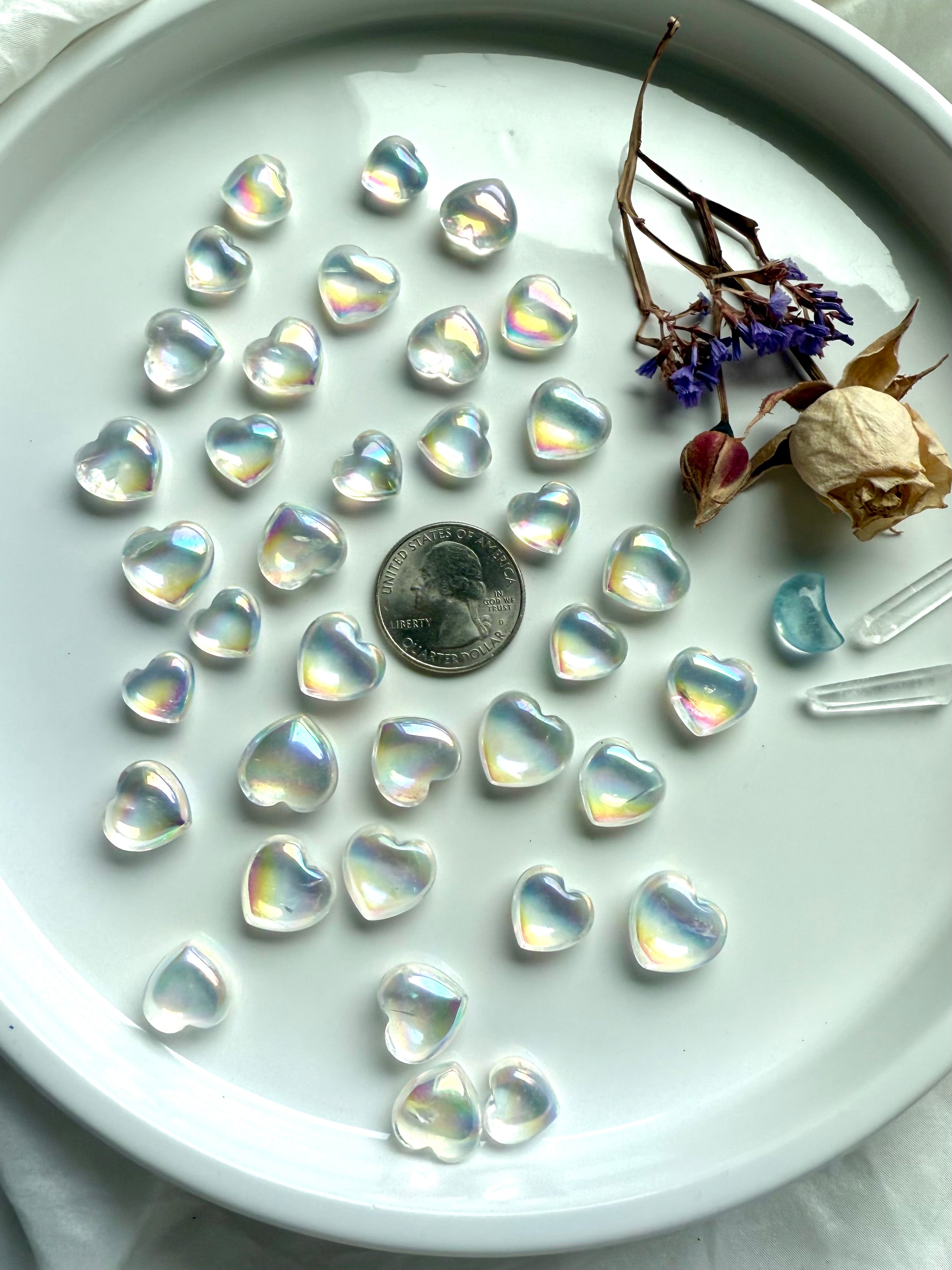 Mini aura quartz hearts in a dish with a US quarter for size reference and scale