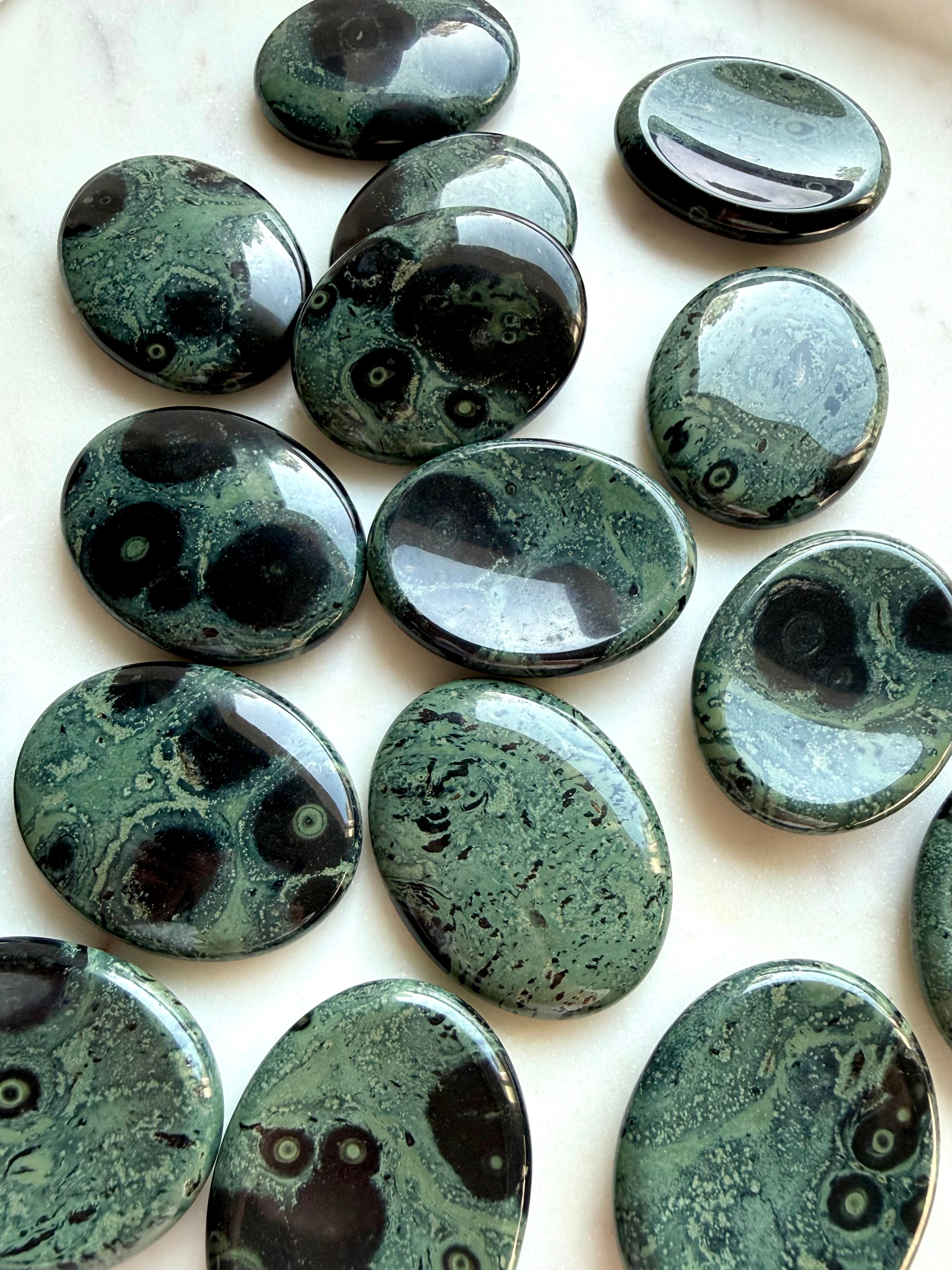 Natural Kambaba Jasper worry stones showing varied green and black orbicular patterns, polished crystals for calm and stress relief