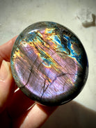Purple Rainbow Labradorite palm stone with vibrant violet, aqua, blue and gold flash revealed in directional lighting