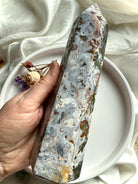 Cosmic Ocean Jasper crystal tower held in hand, featuring swirling blue-gray chalcedony patterns with earthy moss inclusions and natural druzy pockets