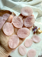 multiple rose quartz worry stones shown on hand for size scale, calming crystals for meditation