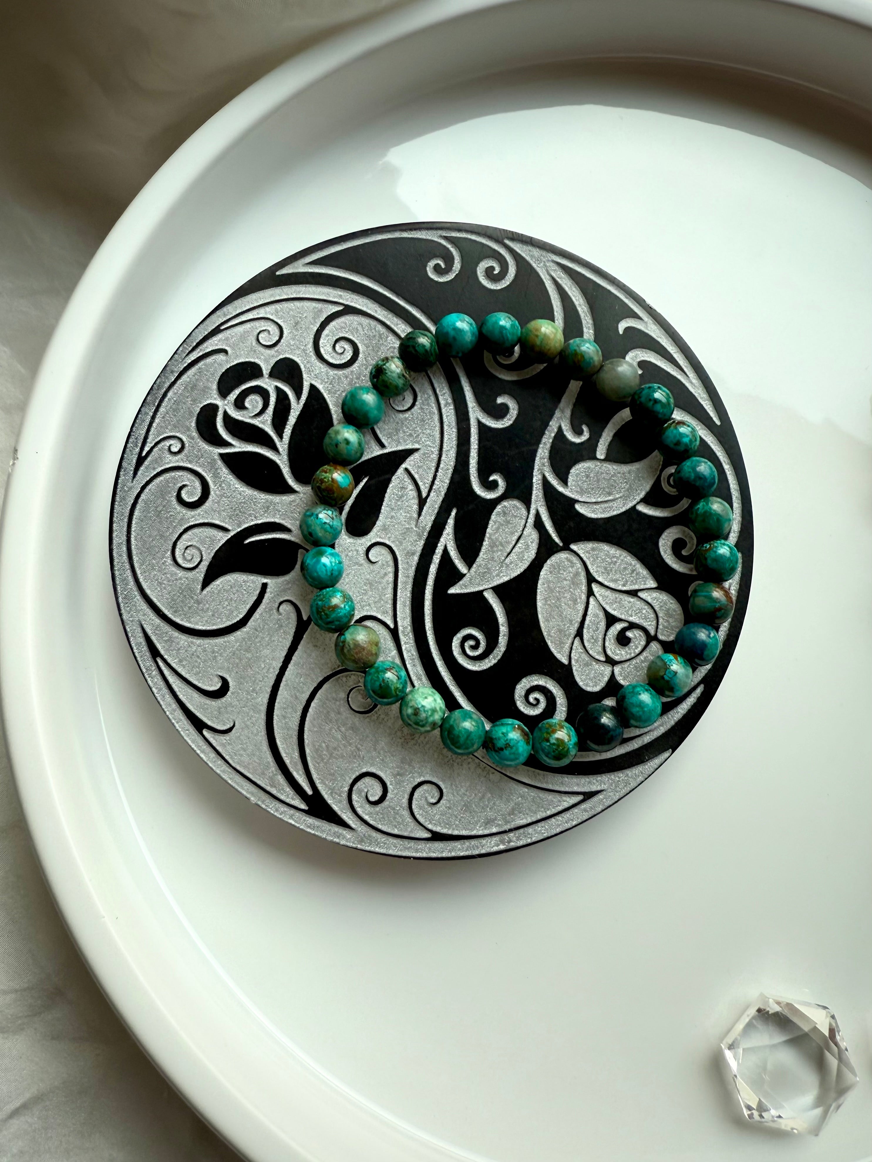 Gemstone bracelet resting on yin yang rose selenite charging plate for crystal cleansing and recharging