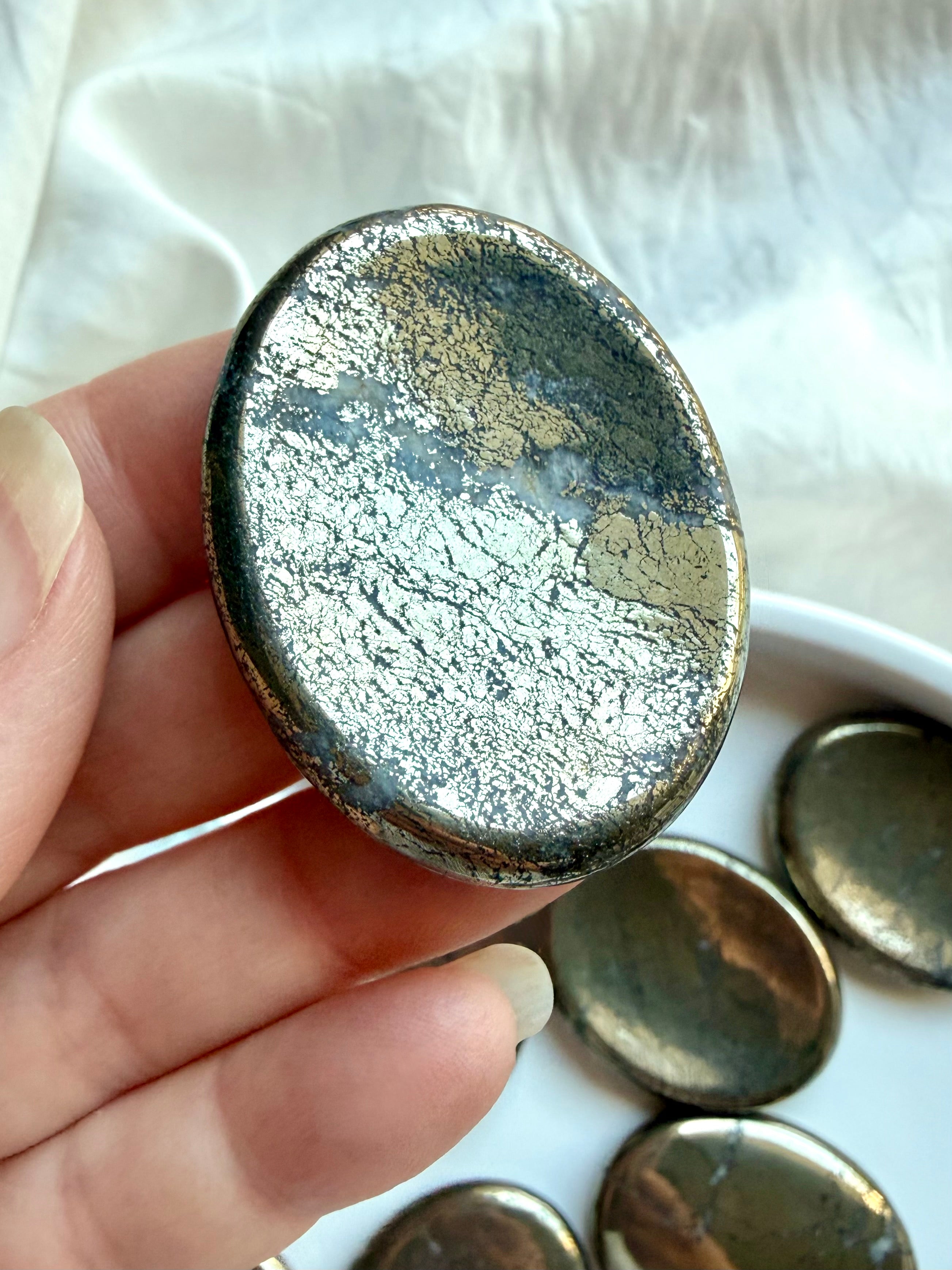 Pyrite worry stone close-up showing reflective gold surface, crystalline texture and natural patina