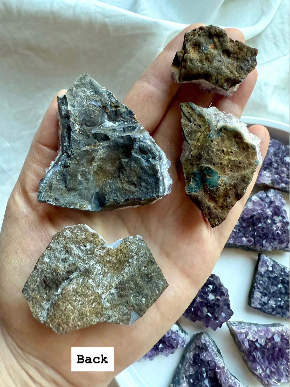 Back view of four amethyst crystal clusters with natural geode matrix crust