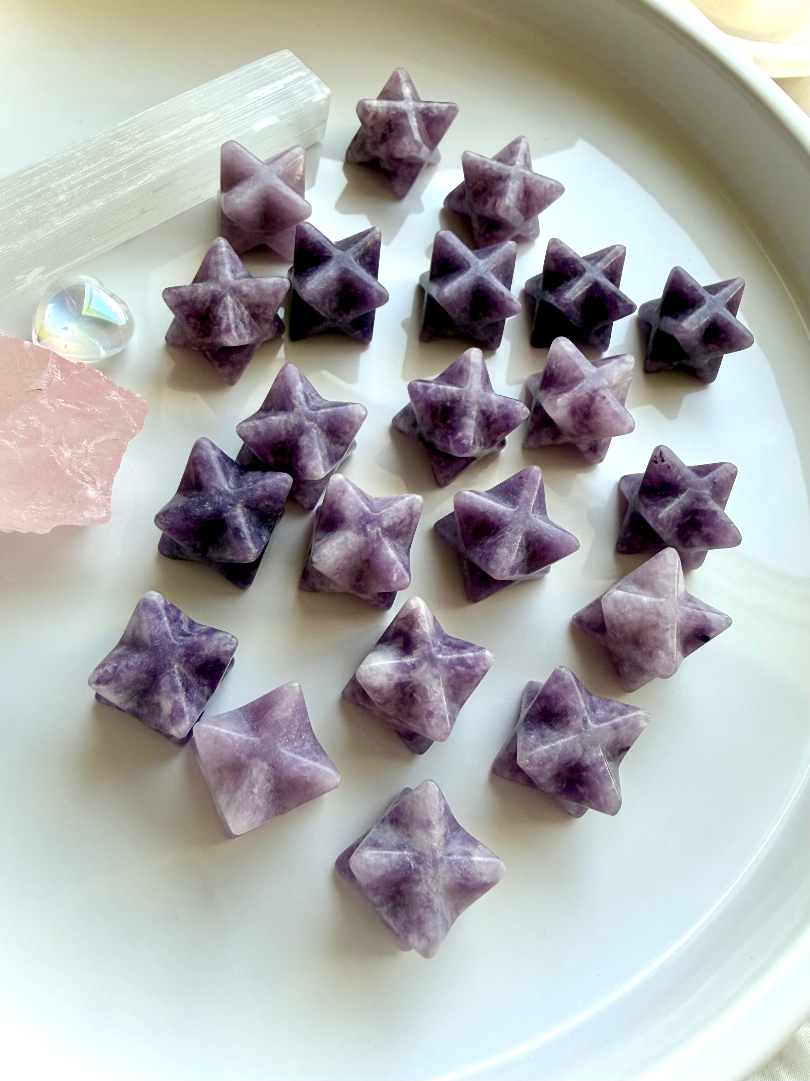 overhead view of lepidolite merkaba star assortment on marble, mini crystal stars for meditation, calm and clarity