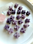 overhead view of lepidolite merkaba star assortment on marble, mini crystal stars for meditation, calm and clarity