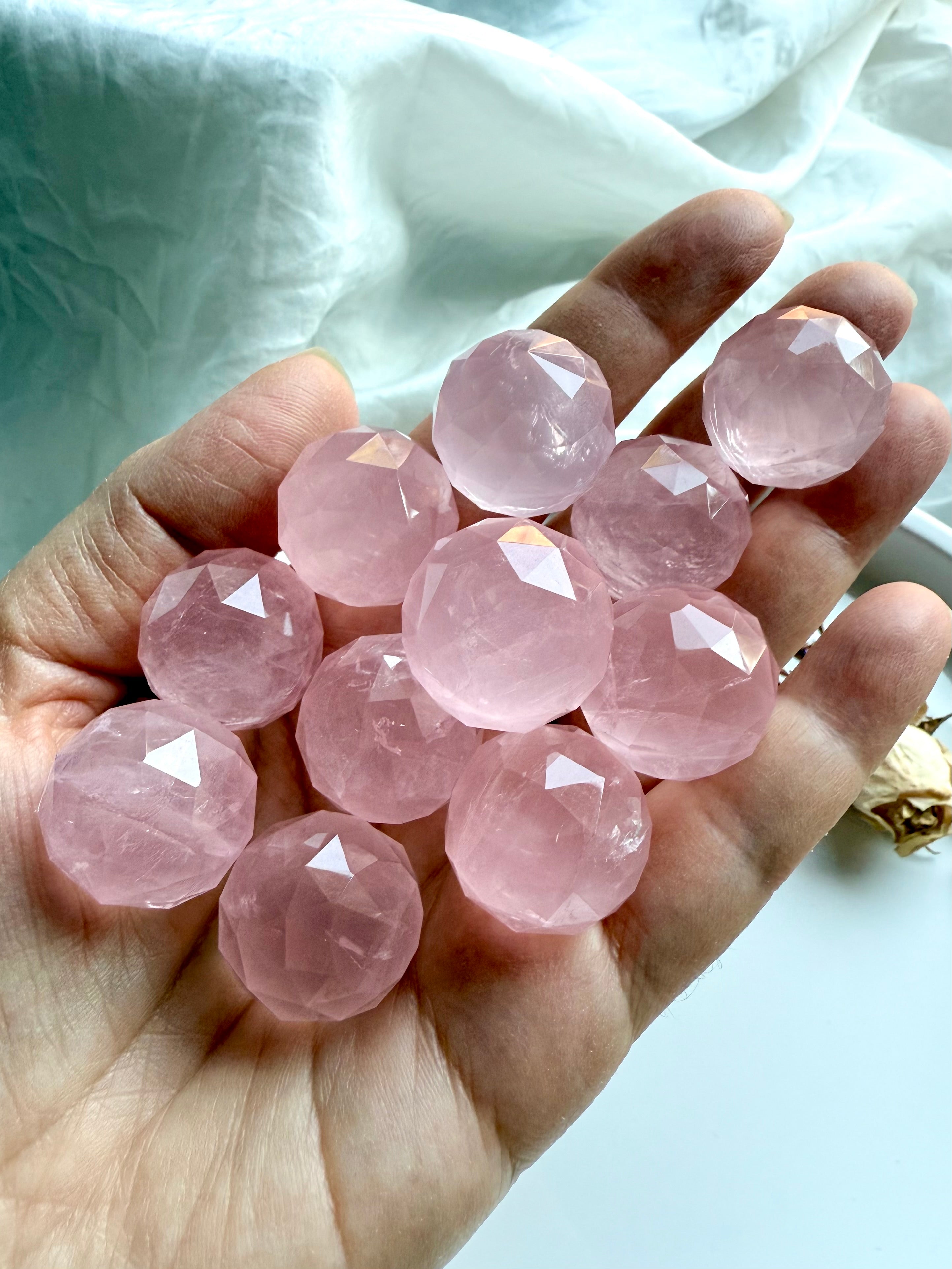 Hand holding high quality rose quartz crystal spheres. Heart chakra healing stones for love.