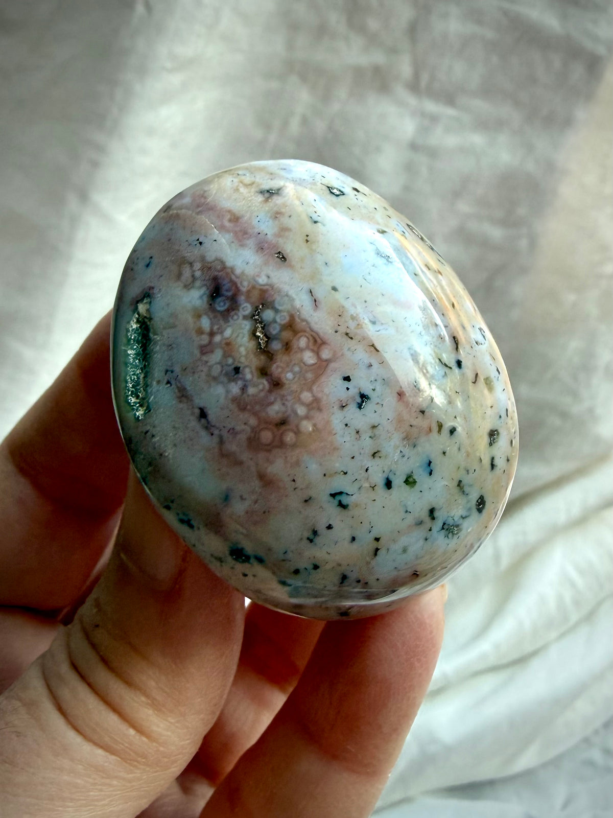 Natural Ocean Jasper palm stone with cream, gray, and earthy mineral inclusions, polished smooth with unique organic markings