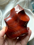 Red Ocean Jasper flame sculpture featuring layered red banding and organic landscape-like markings. 