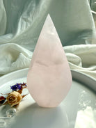 Mangano Calcite flame crystal in hand for size reference with luminous pink color and subtle internal patterning