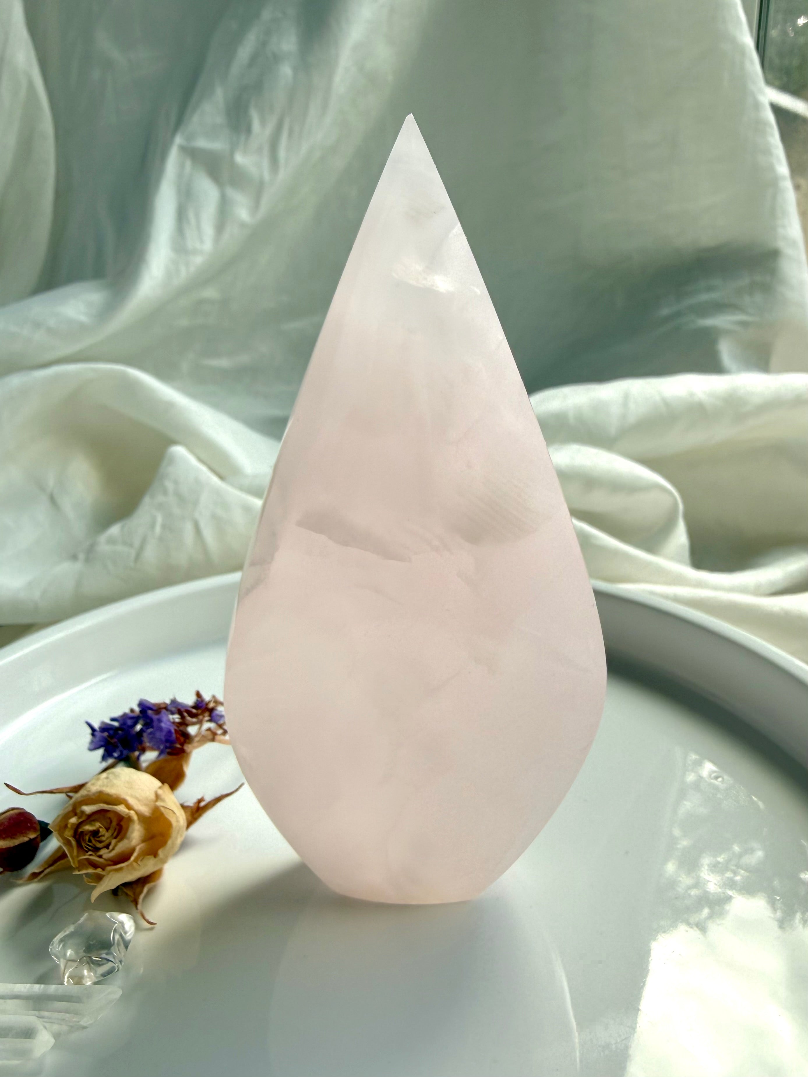 Mangano Calcite flame crystal in hand for size reference with luminous pink color and subtle internal patterning