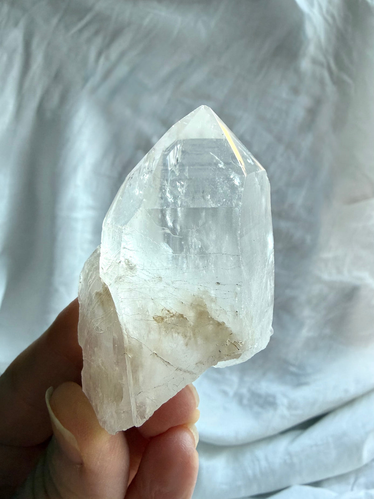 Natural Lemurian Quartz crystal point held in hand with rough matrix, cloudy inclusions, and distinctive growth markings